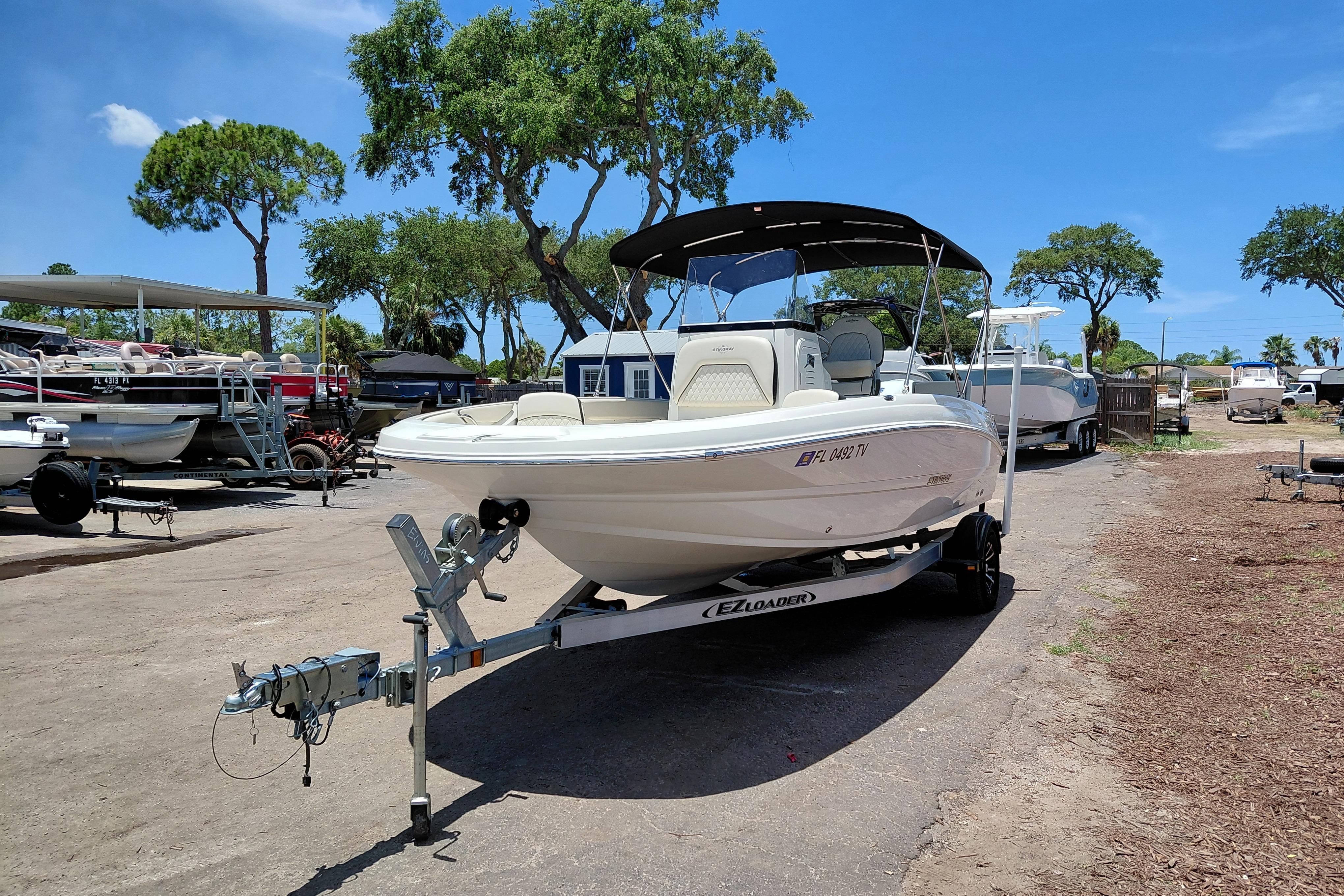 2023 Stingray 206 CC boat on trailer, parked outdoors under clear blue sky.