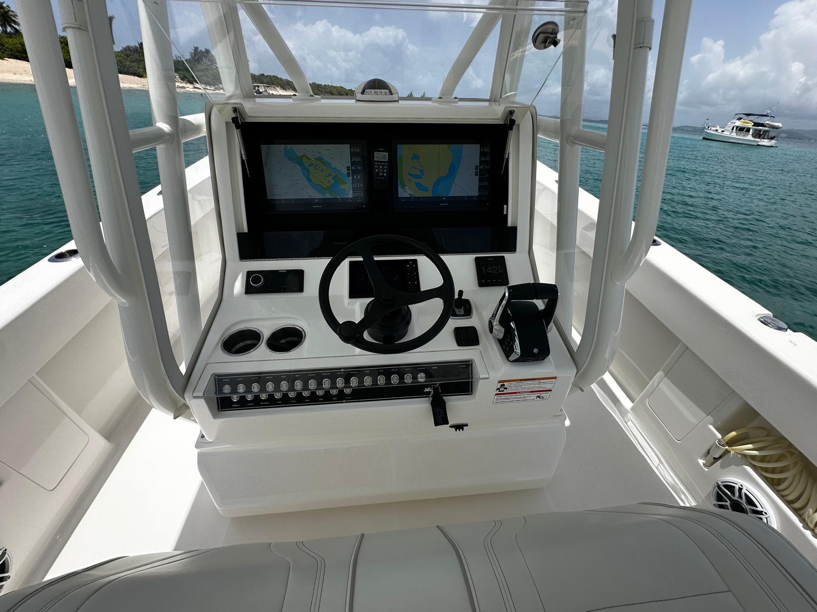 2024 SeaVee 340Z boat console with dual screens and steering wheel, docked near a tropical beach.