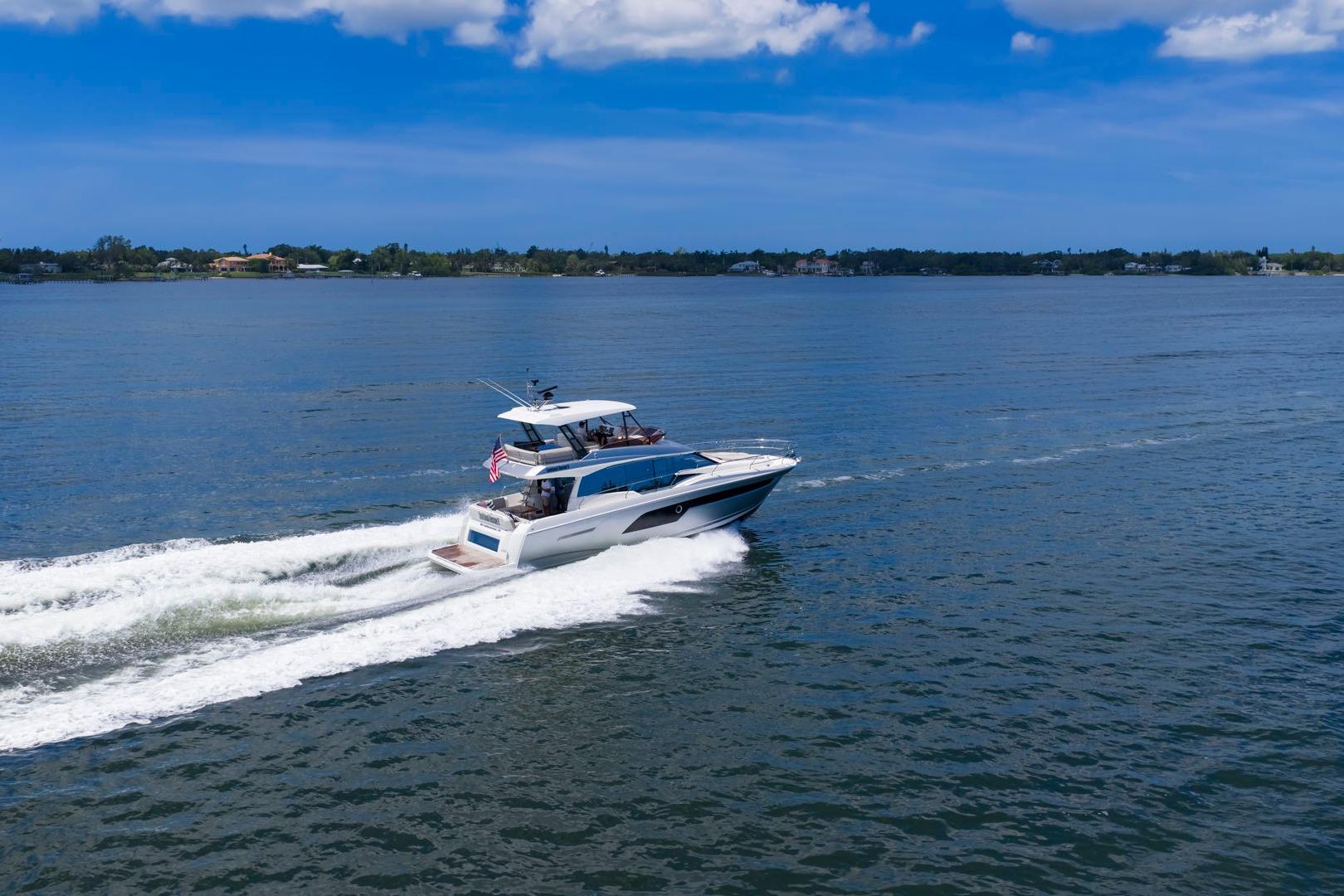 2022 Prestige 520 yacht cruising on a serene blue lake under a clear sky.