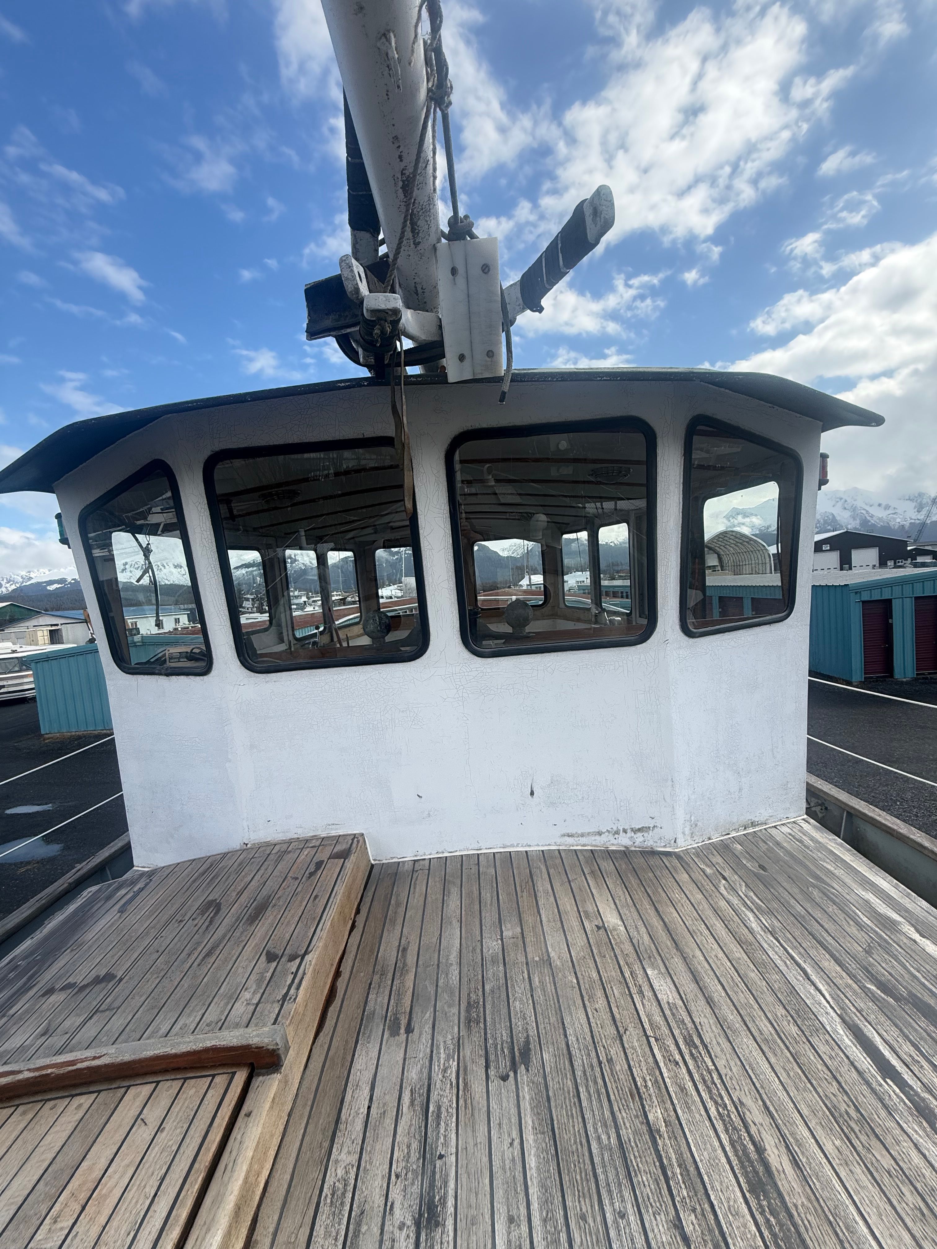A wooden deck of a schooner sailboat with a cabin and windows.