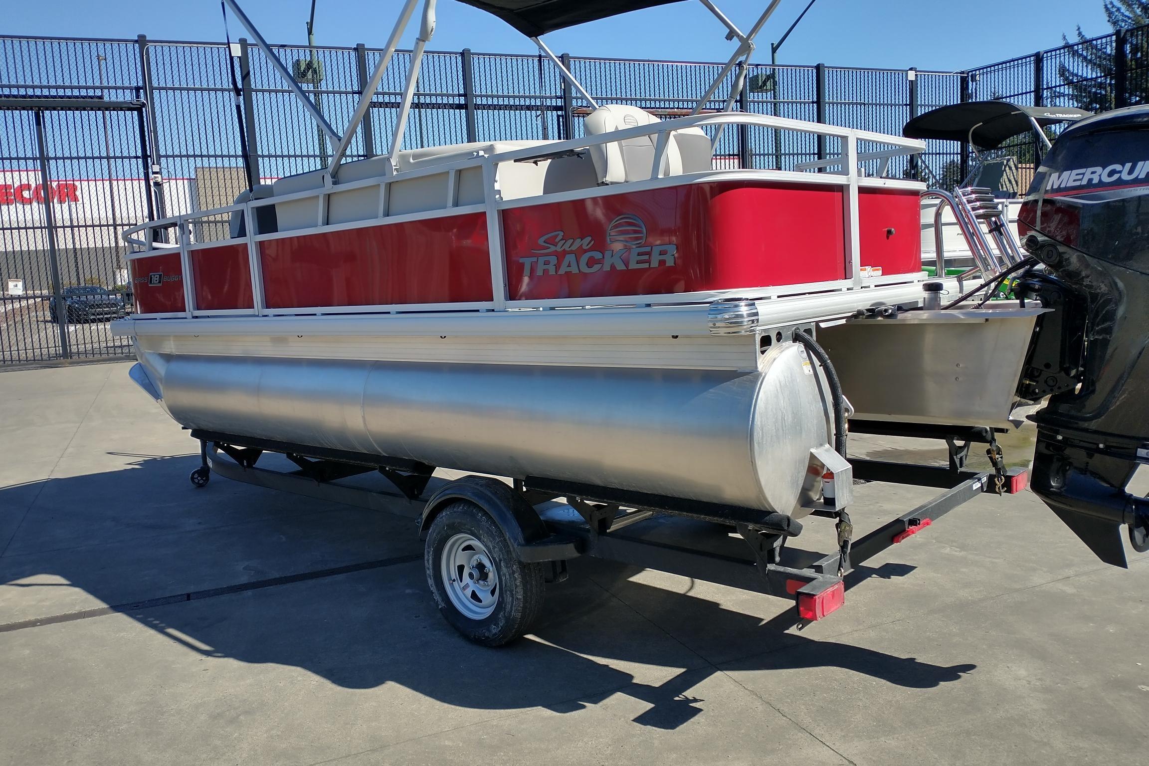 2026 Sun Tracker Bass Buggy 18 DLX pontoon boat on trailer, red and silver design.