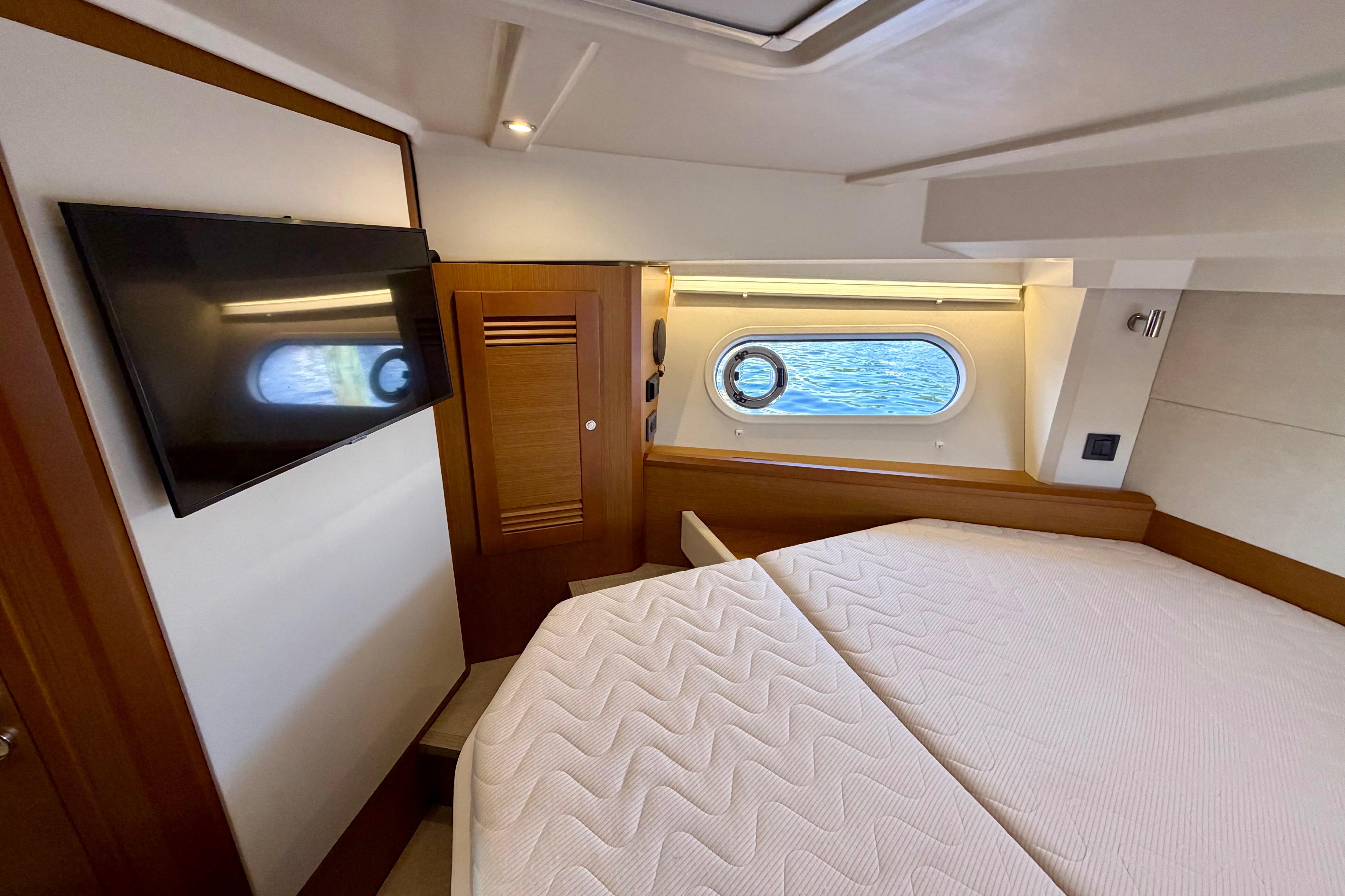 Luxurious cabin interior of 2025 Beneteau Swift Trawler 41 Fly with TV and porthole view.