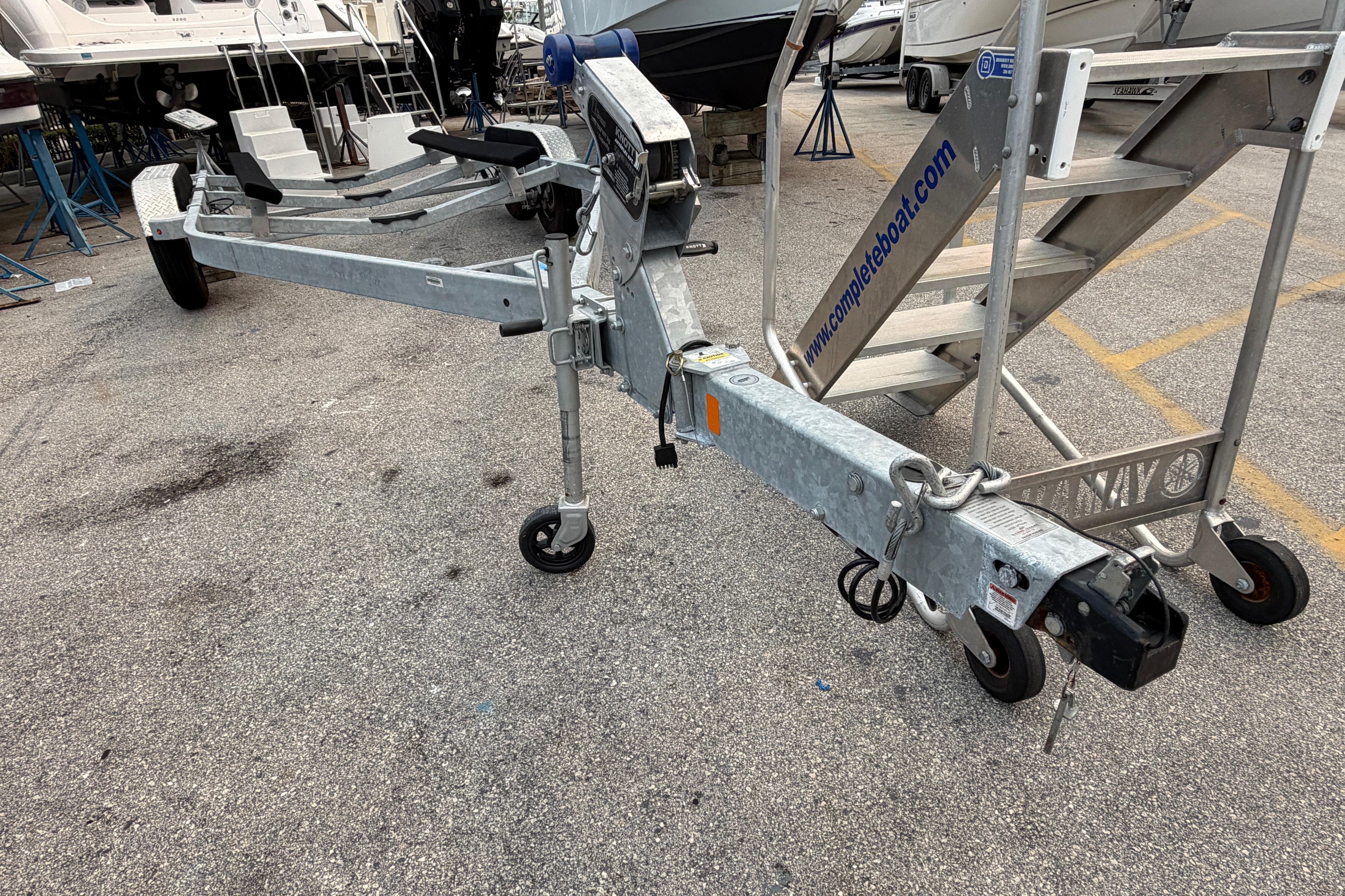 2024 SRT5000 boat trailer with metal frame and wheels in a marina setting.