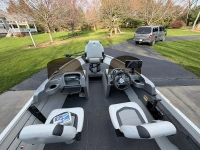 A Crestliner boat on a trailer in a driveway, featuring two seats and a steering console.