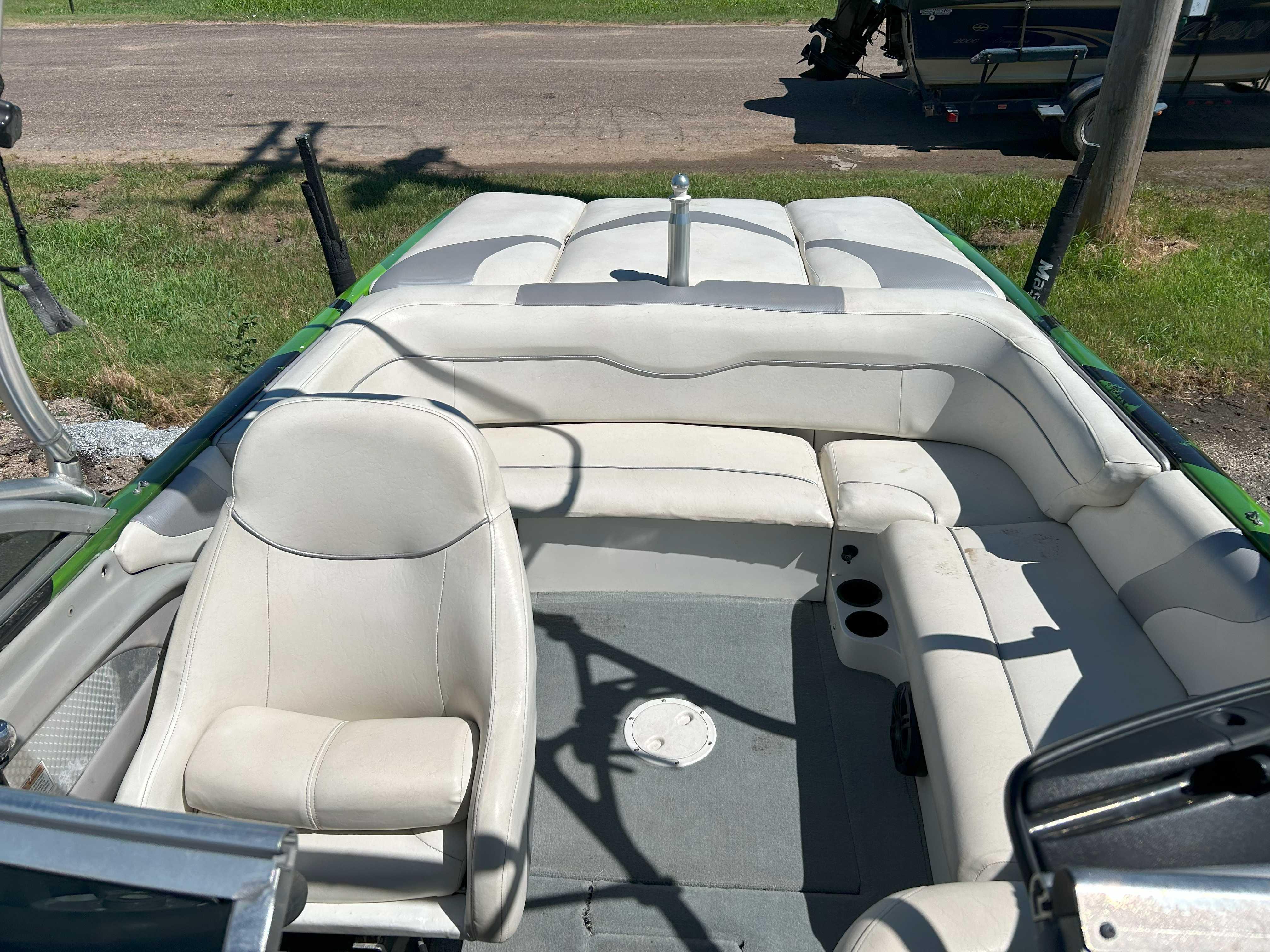 2002 MasterCraft XStar boat interior with white seating and green accents, parked on grass.