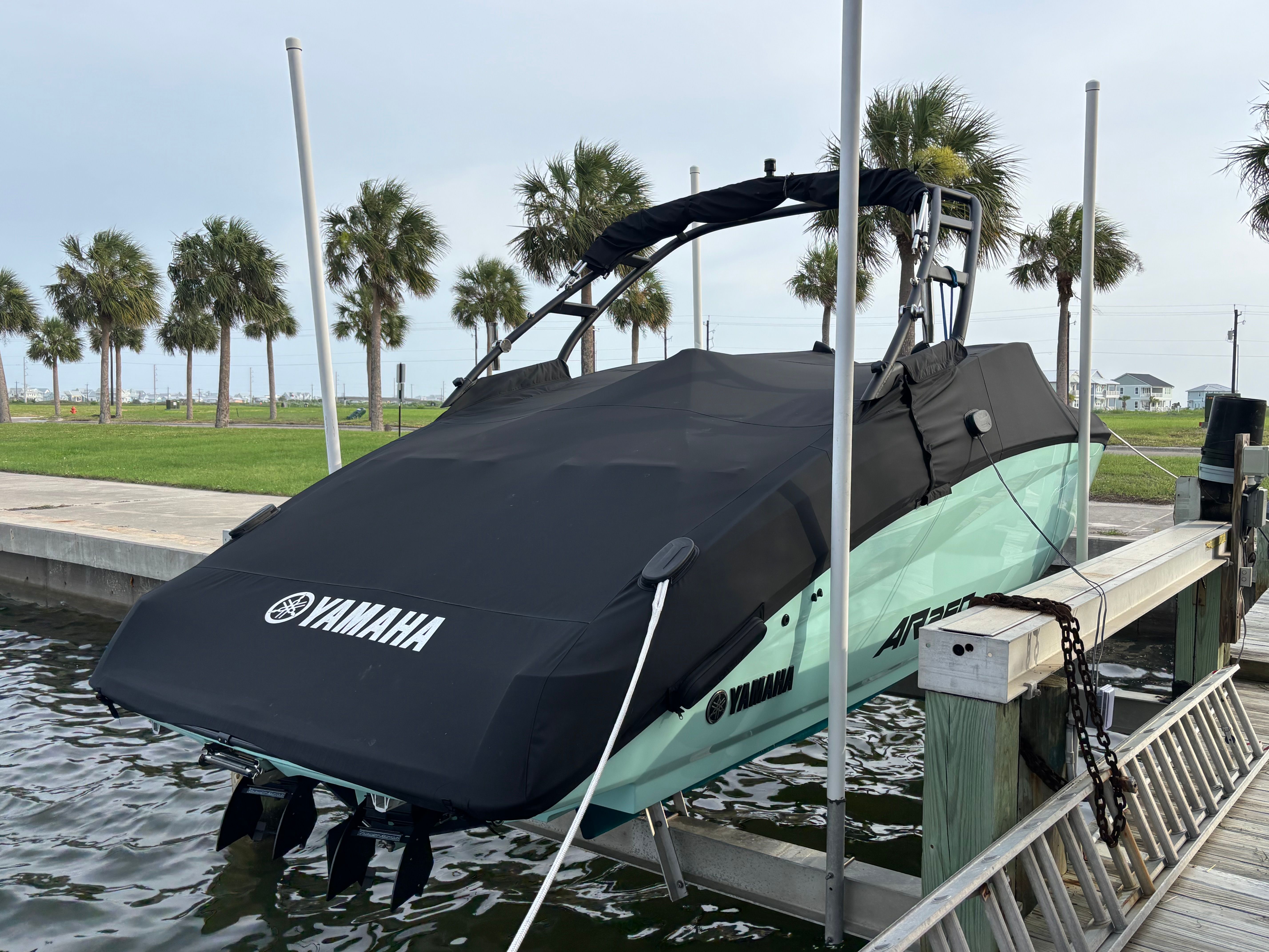 A 2024 Yamaha AR250 boat is on a boat lift by the water.
