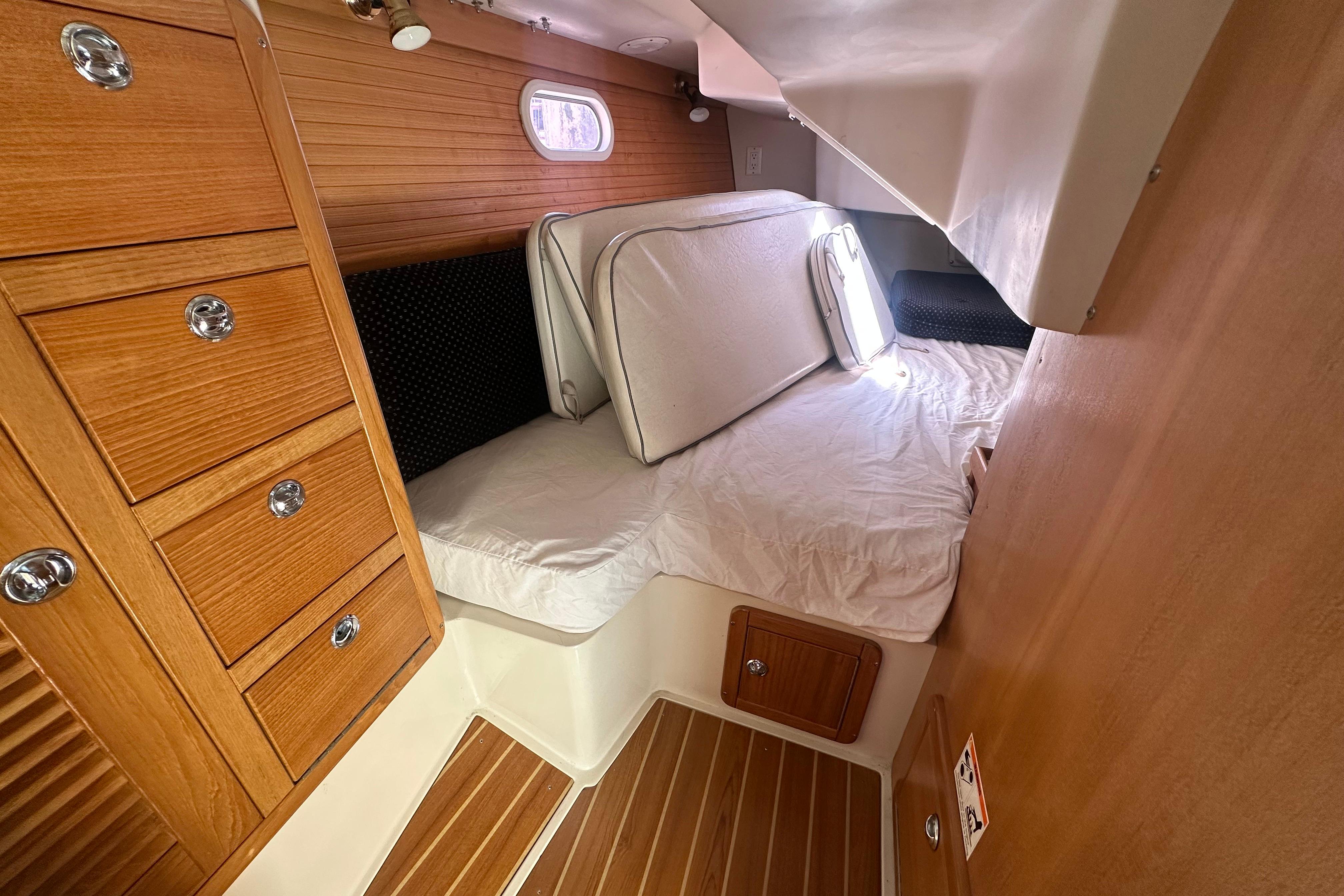 Cozy cabin interior of 2005 Catalina 36 MkII sailboat with wooden cabinetry and bedding.