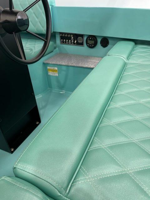2023 Vision Marine Technologies Fantail 217 interior with teal quilted seating and steering wheel.