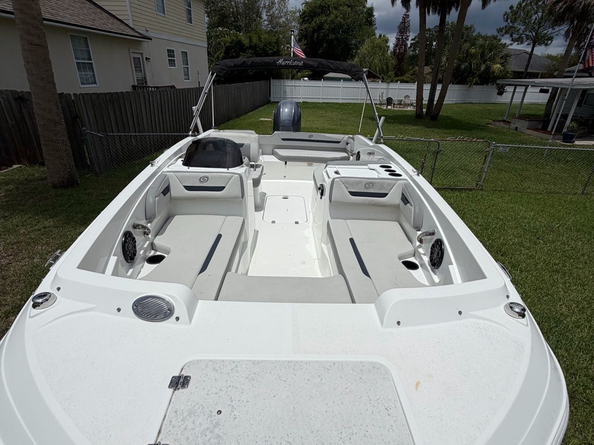 The image shows a 2021 Hurricane SunDeck Sport 205 OB boat on a lawn. It features white upholstery and an outboard motor.