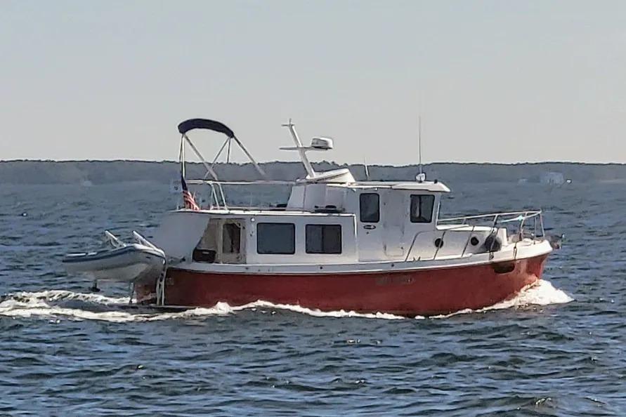 2006 American Tug AT cruising on open water with a small boat attached.
