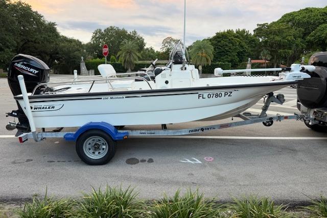 2016 Boston Whaler 150 Montauk boat on trailer, parked outdoors.