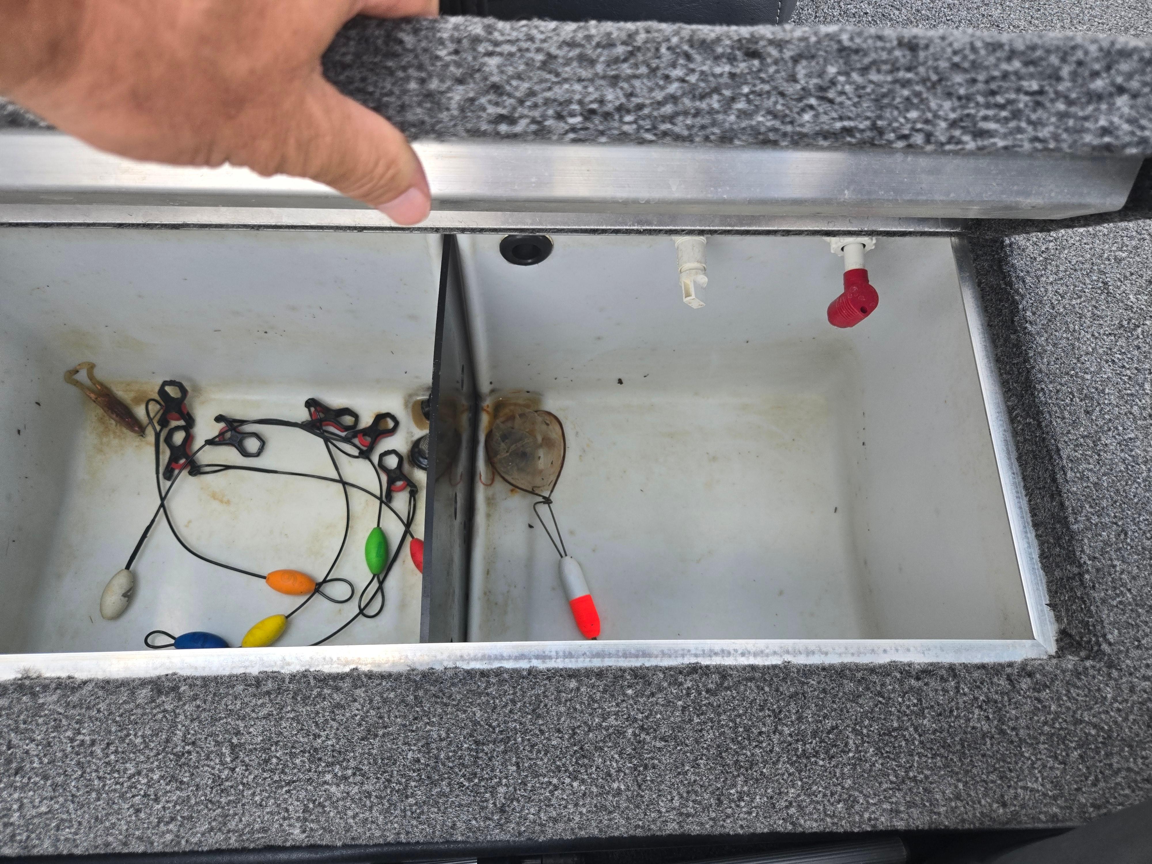 Open storage compartment in 2021 Lowe Stinger 188 boat with fishing gear inside.
