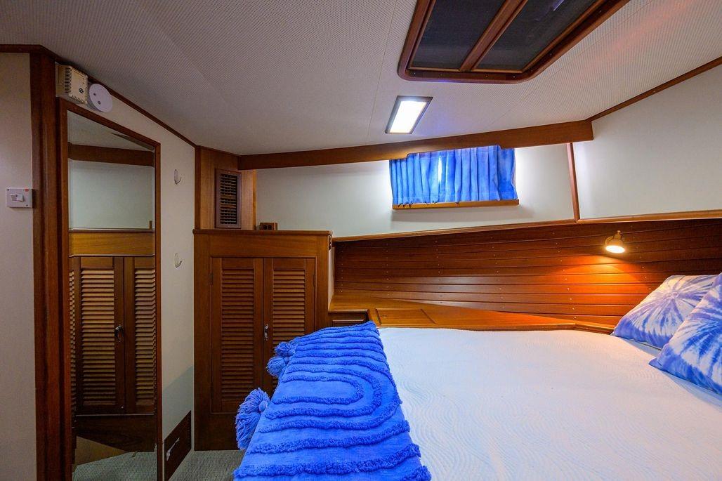 Cozy cabin interior of 1999 Grand Banks 42 Europa with blue bedding and wooden accents.