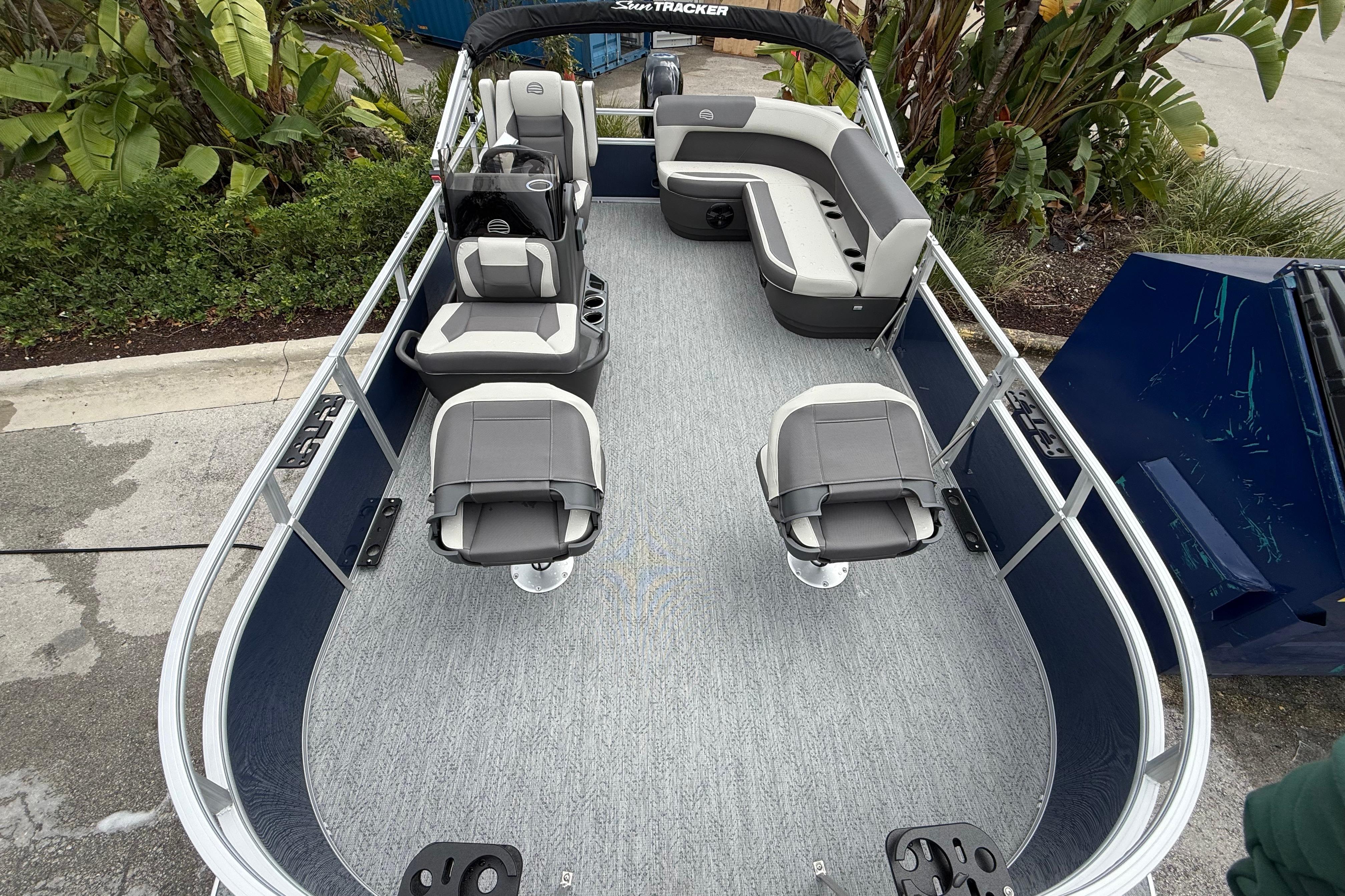 2026 Sun Tracker Bass Buggy 16 XL Select pontoon boat with seating and helm, docked outdoors.