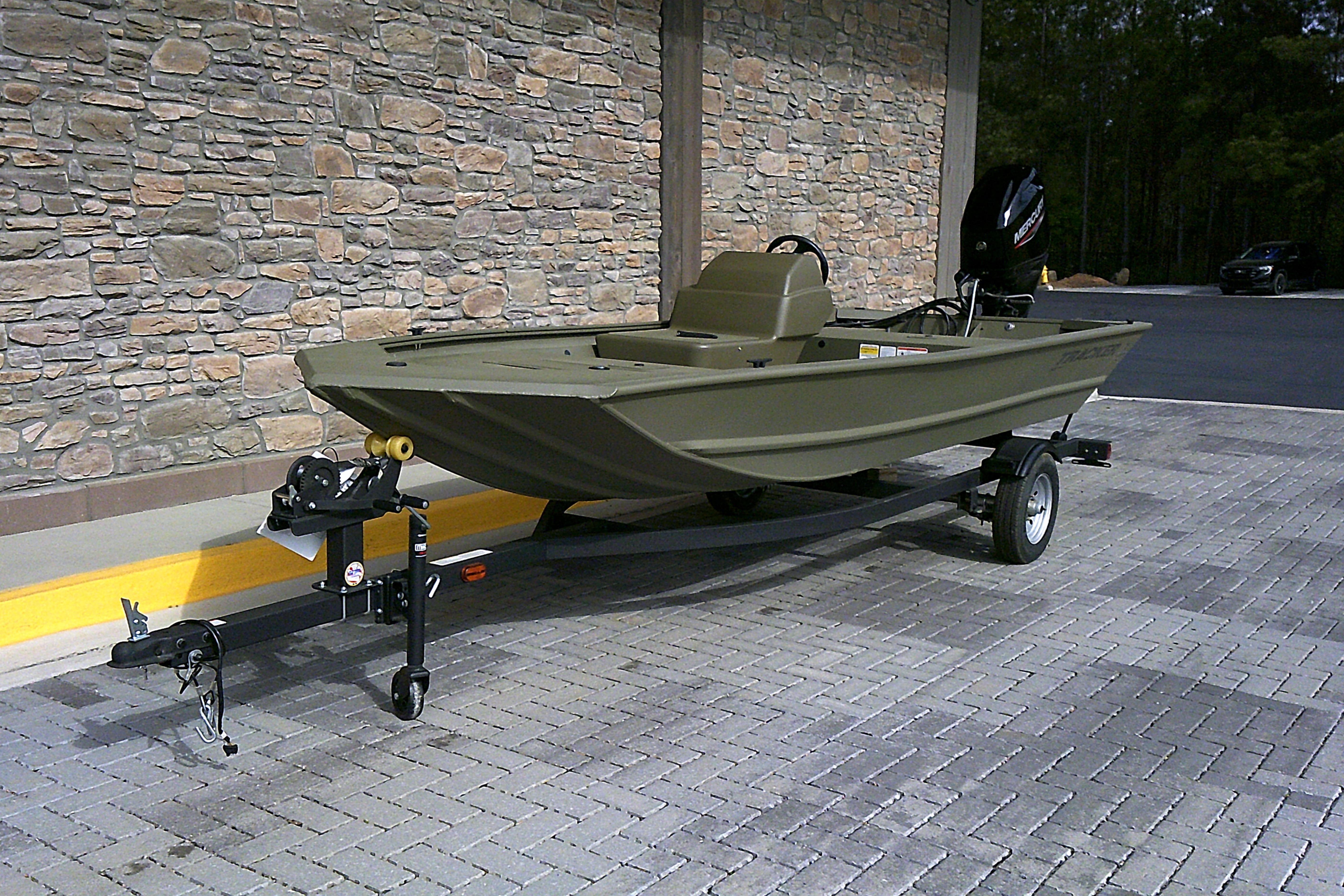 2026 Tracker Grizzly 1648 SC boat on trailer, parked on brick pavement.