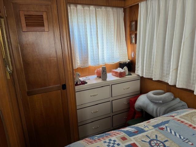 Cozy bedroom with wooden paneling, dresser, and nautical-themed quilt, inside a 1994 Gibson 44 Standard.