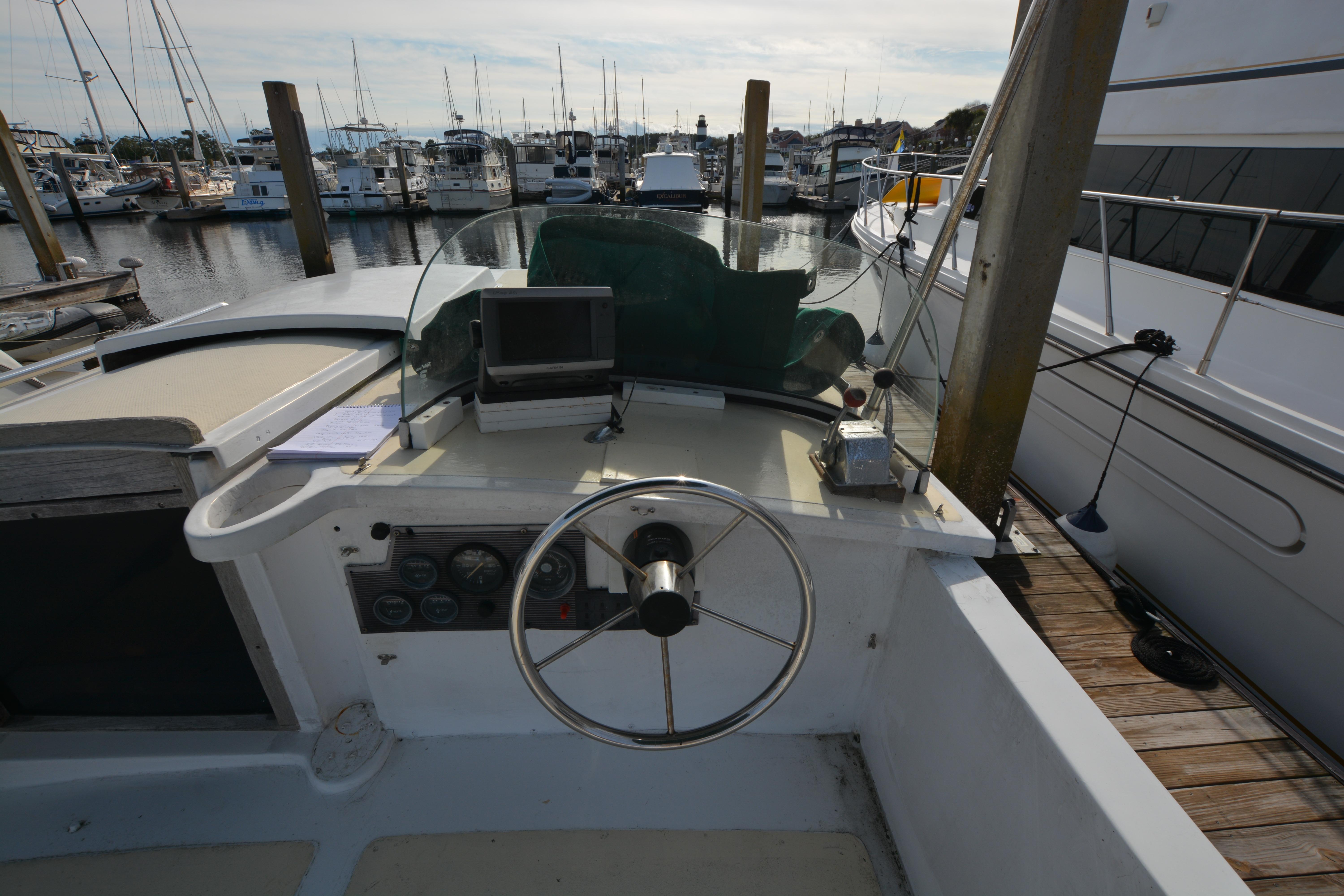 1974 Fales Navigator boat helm with steering wheel and controls, docked at marina.