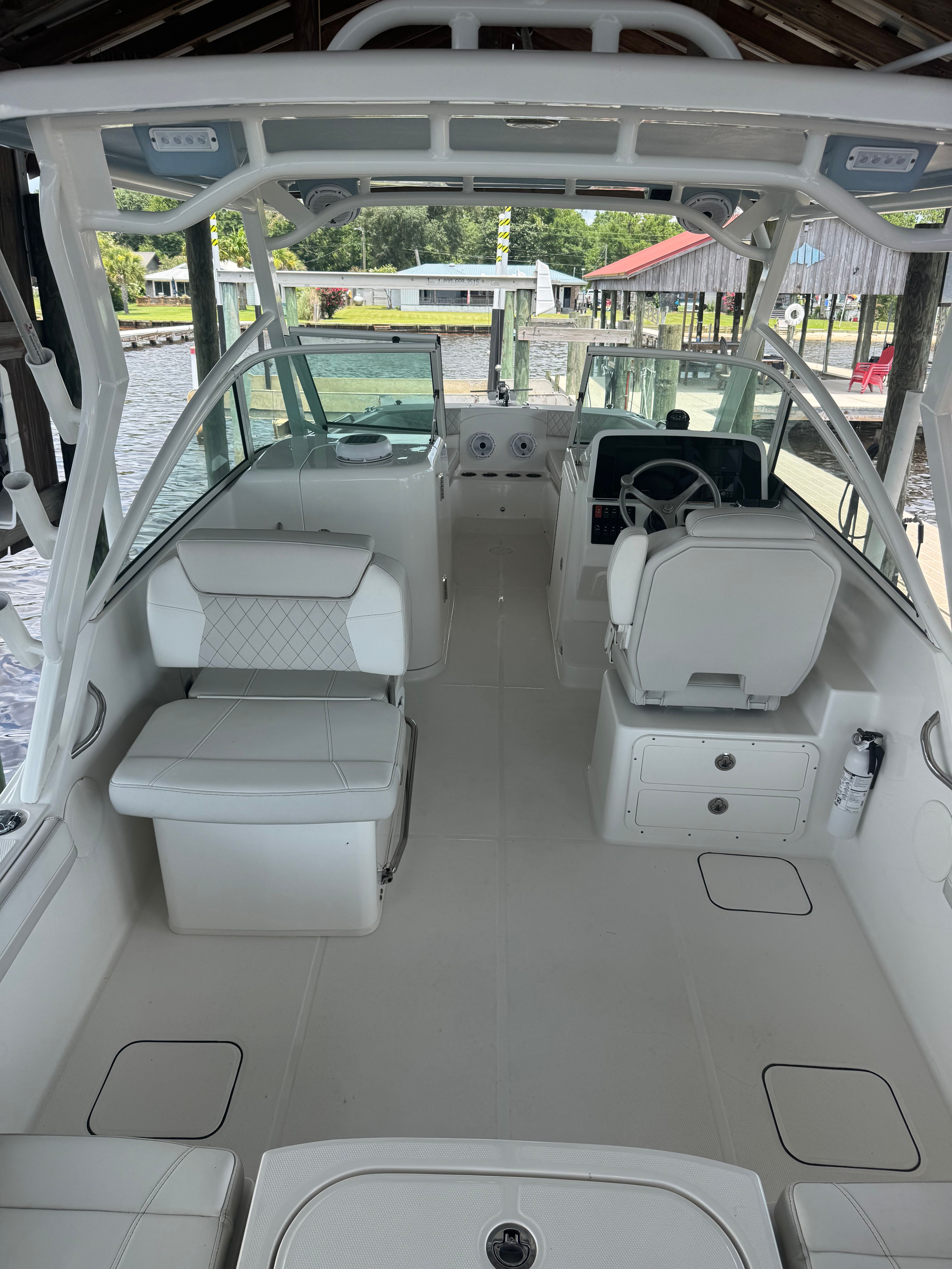 The image shows the cockpit of a 2025 World Cat 230 DC boat with white seating and helm.