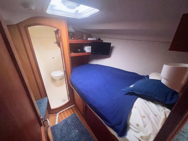 Cabin with bed, TV, and adjoining bathroom on a Hunter 410 boat.