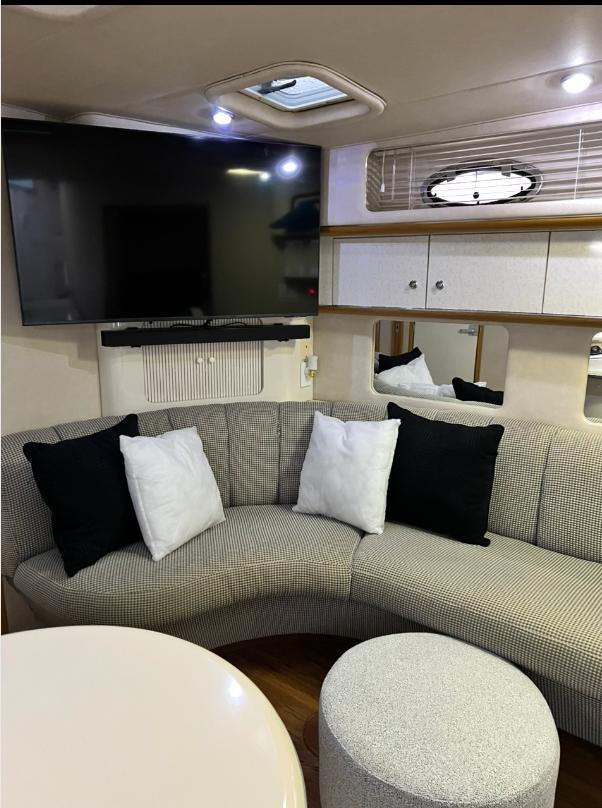 Interior of 1995 Sea Ray 450 Sundancer with curved seating, cushions, and mounted TV.