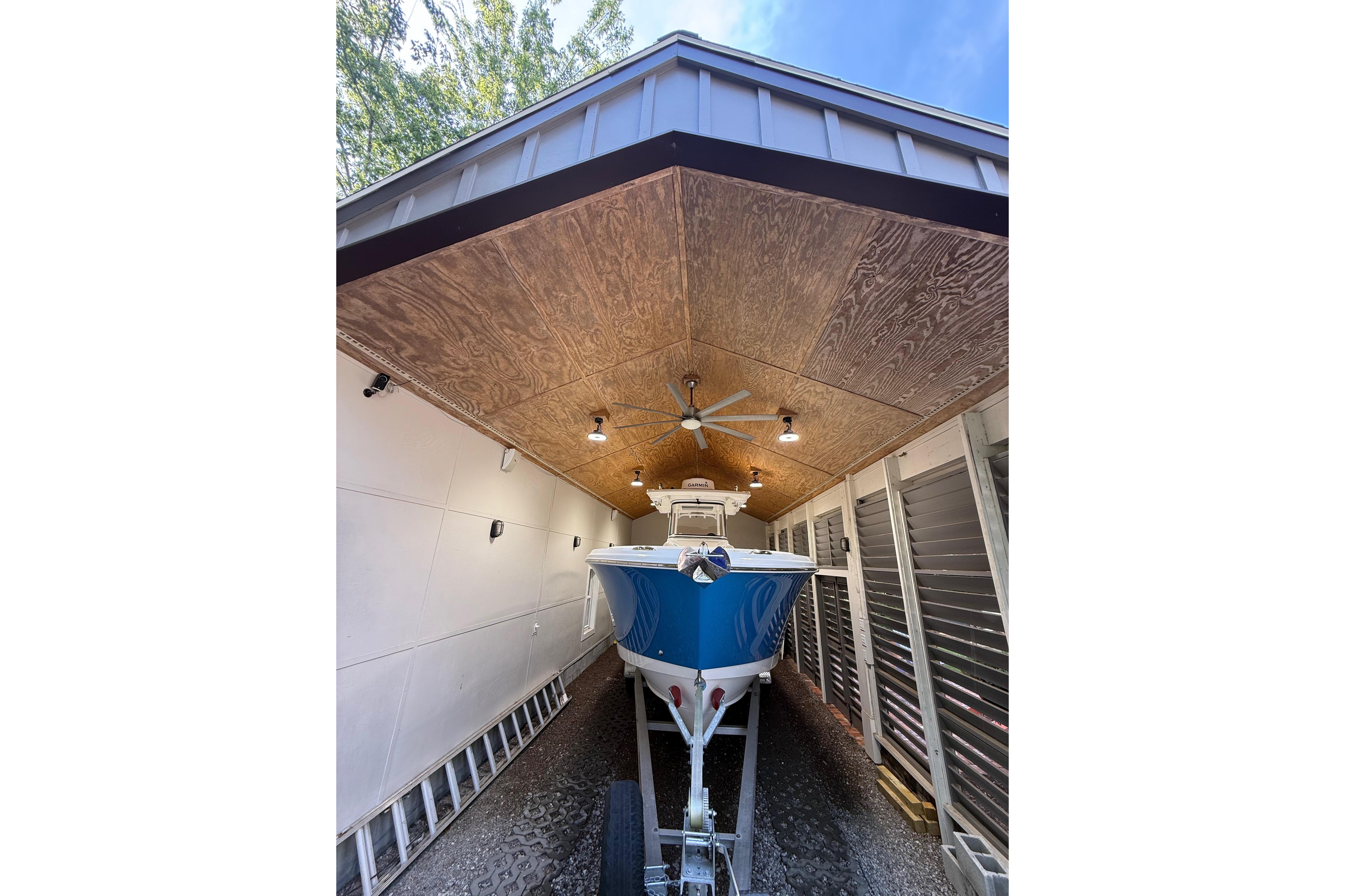 2022 Edgewater 280CC boat stored under a wooden canopy with ceiling fan.