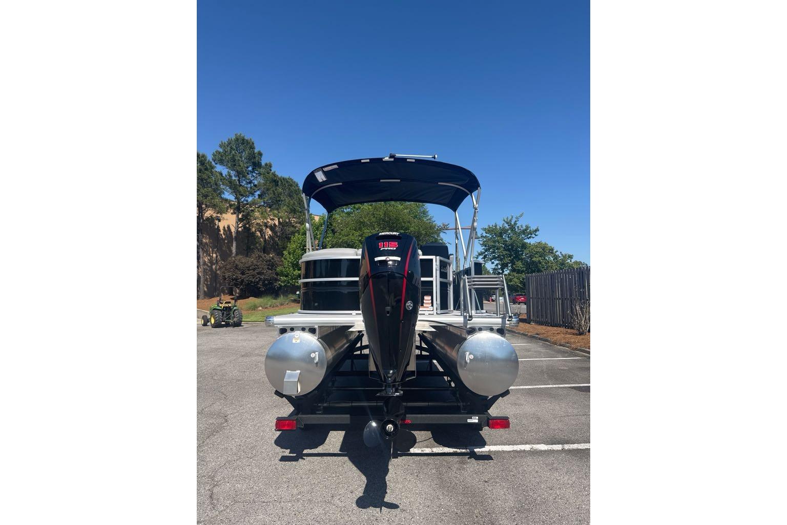 2026 Sun Tracker Party Barge 20 DLX pontoon boat in parking lot, rear view.