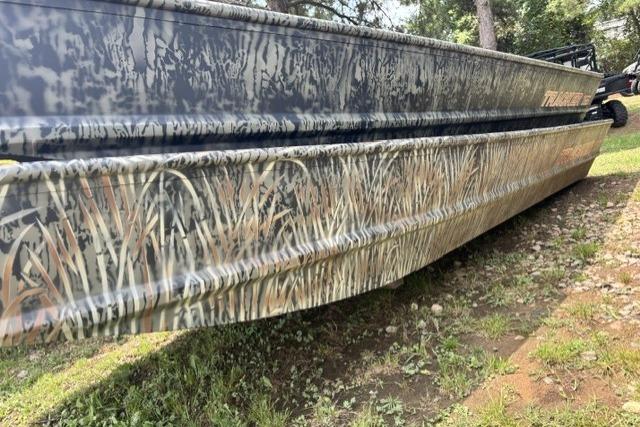 2026 Tracker Grizzly 15 Jon boat with camouflage design on grassy terrain.
