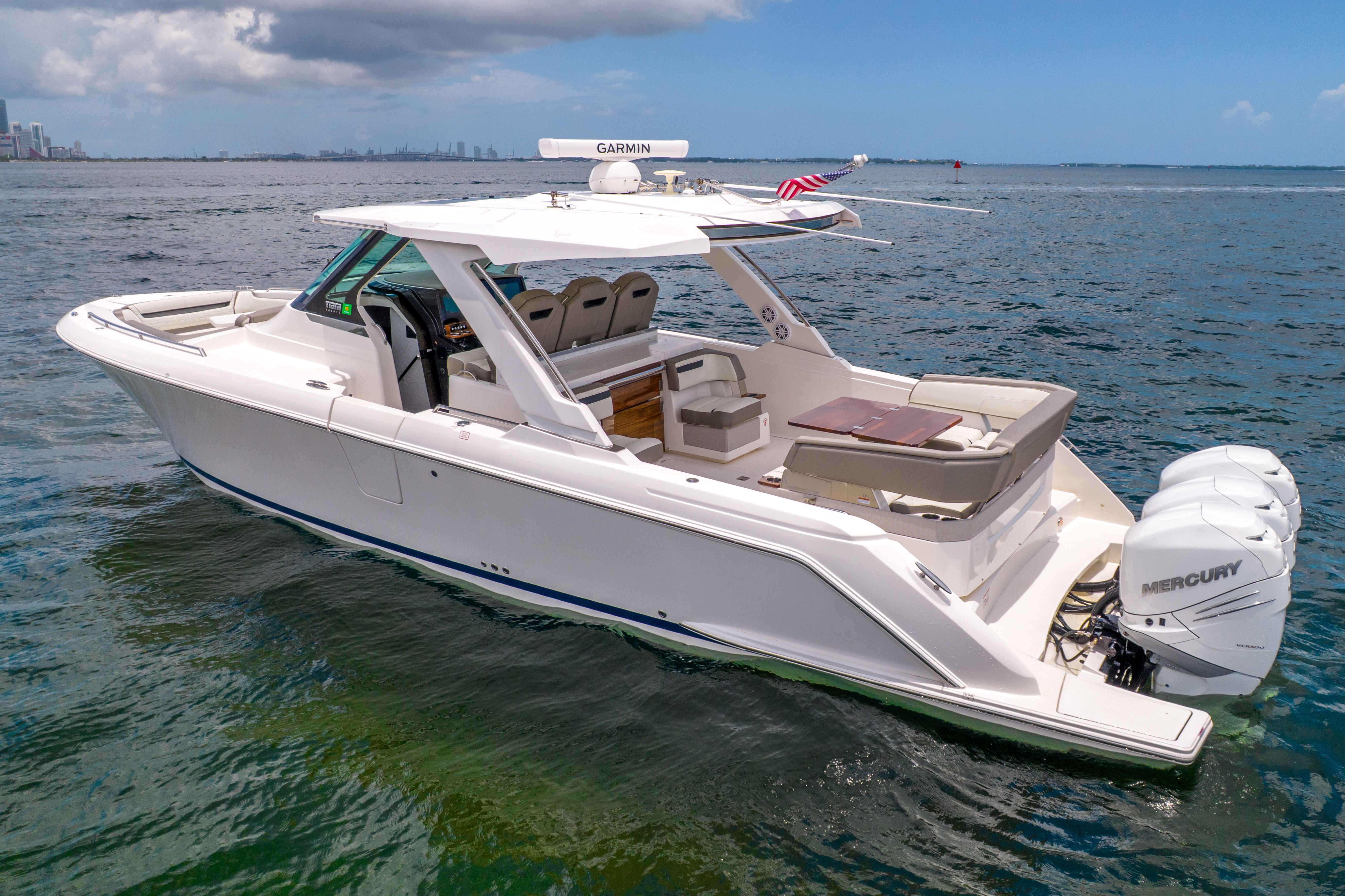A sleek, modern boat with three outboard engines on calm water.