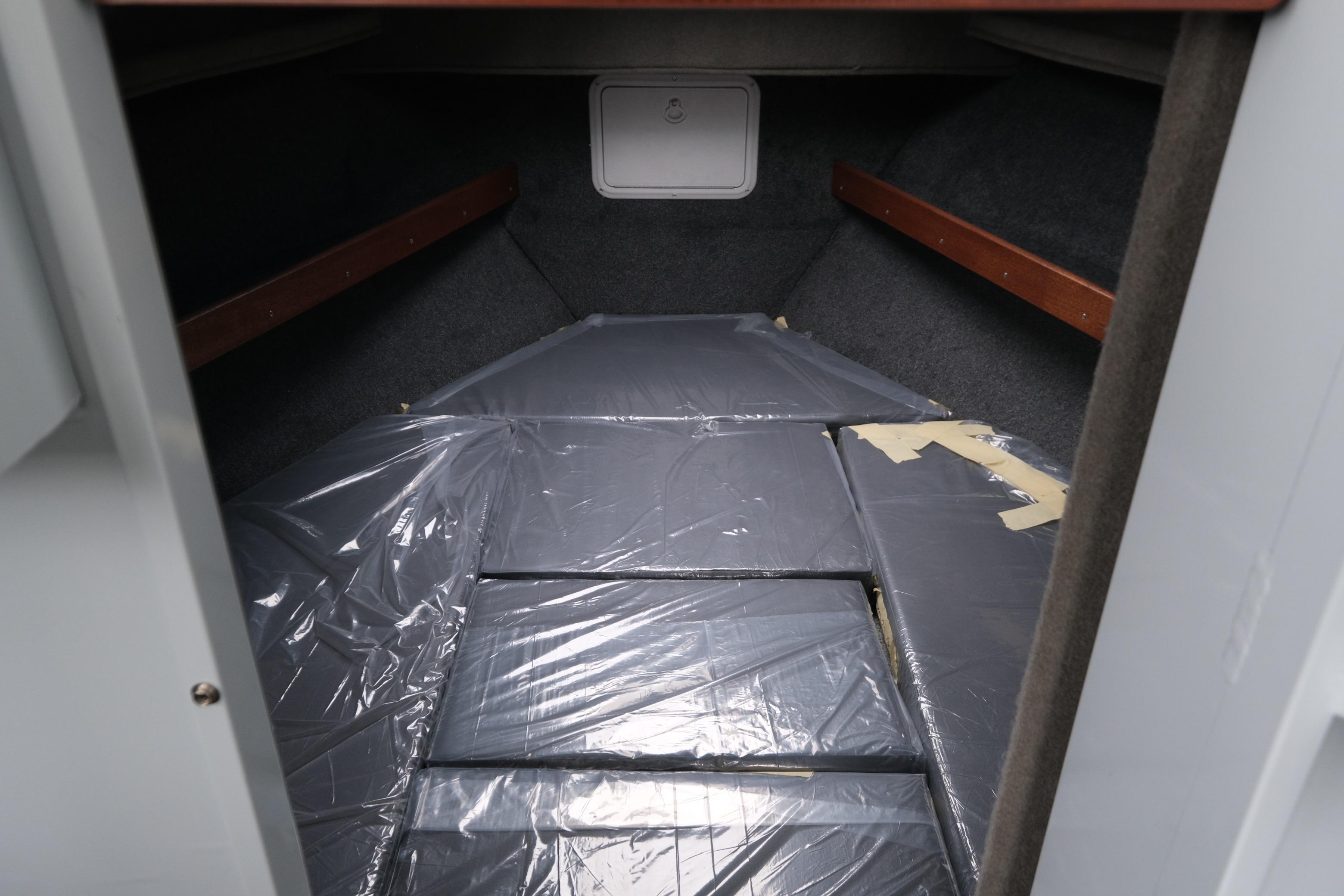 2026 Hewescraft 270 Pacific Explorer cabin interior with plastic-covered bedding.