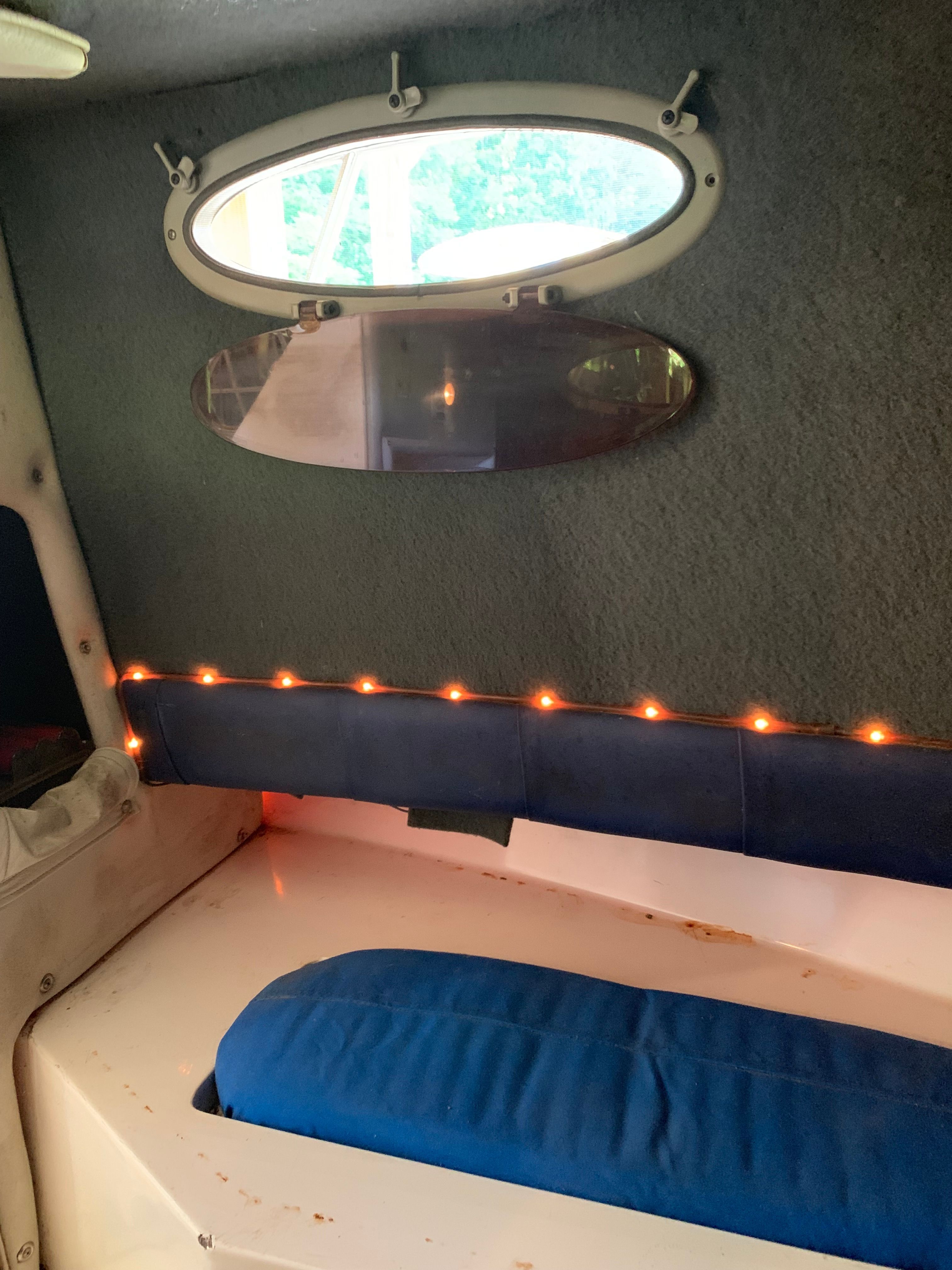 Interior of a 1998 Eurosport 221WA boat with porthole and string lights.