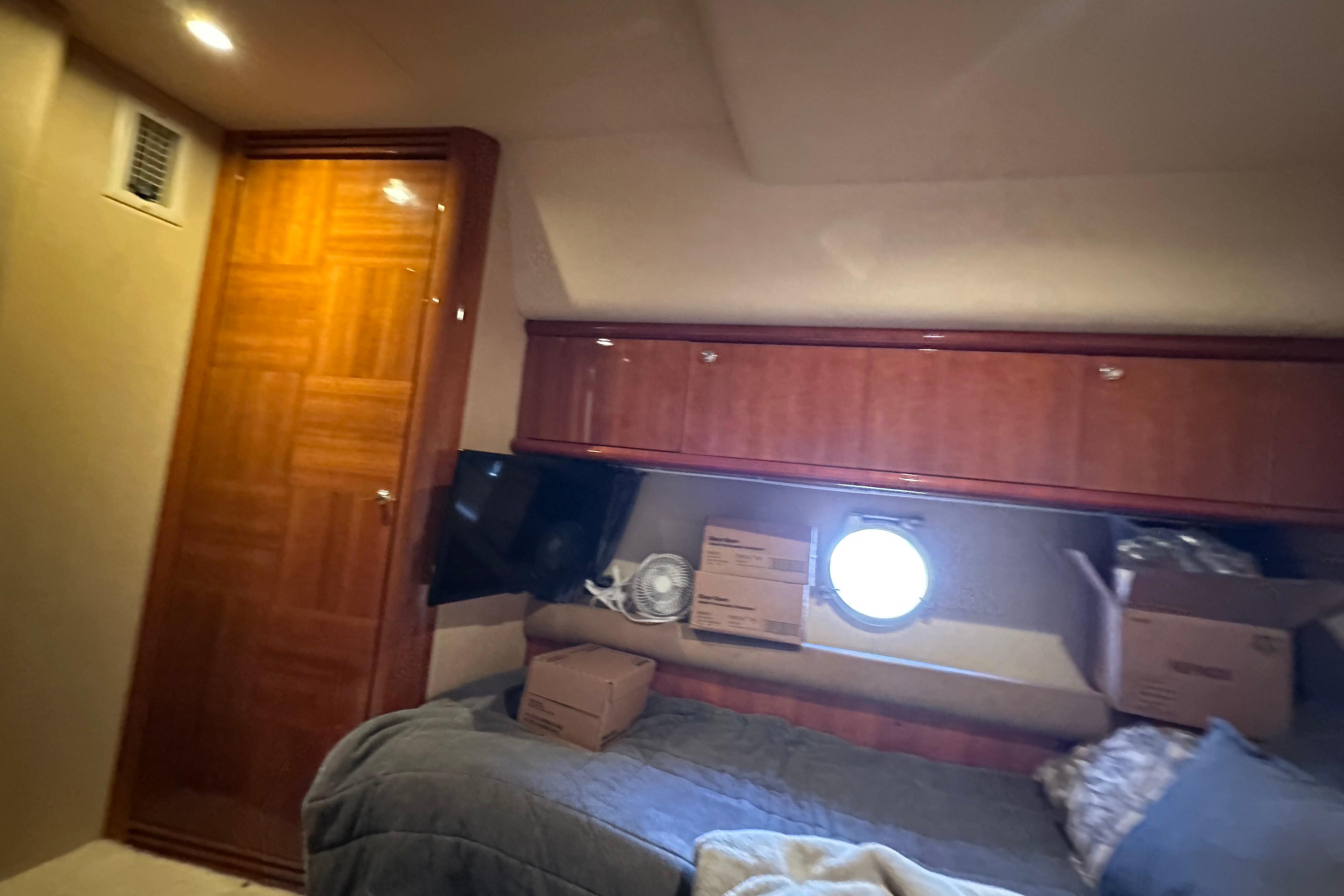 Luxurious cabin interior of a 2004 Azimut 55E yacht with wooden cabinetry and cozy bedding.