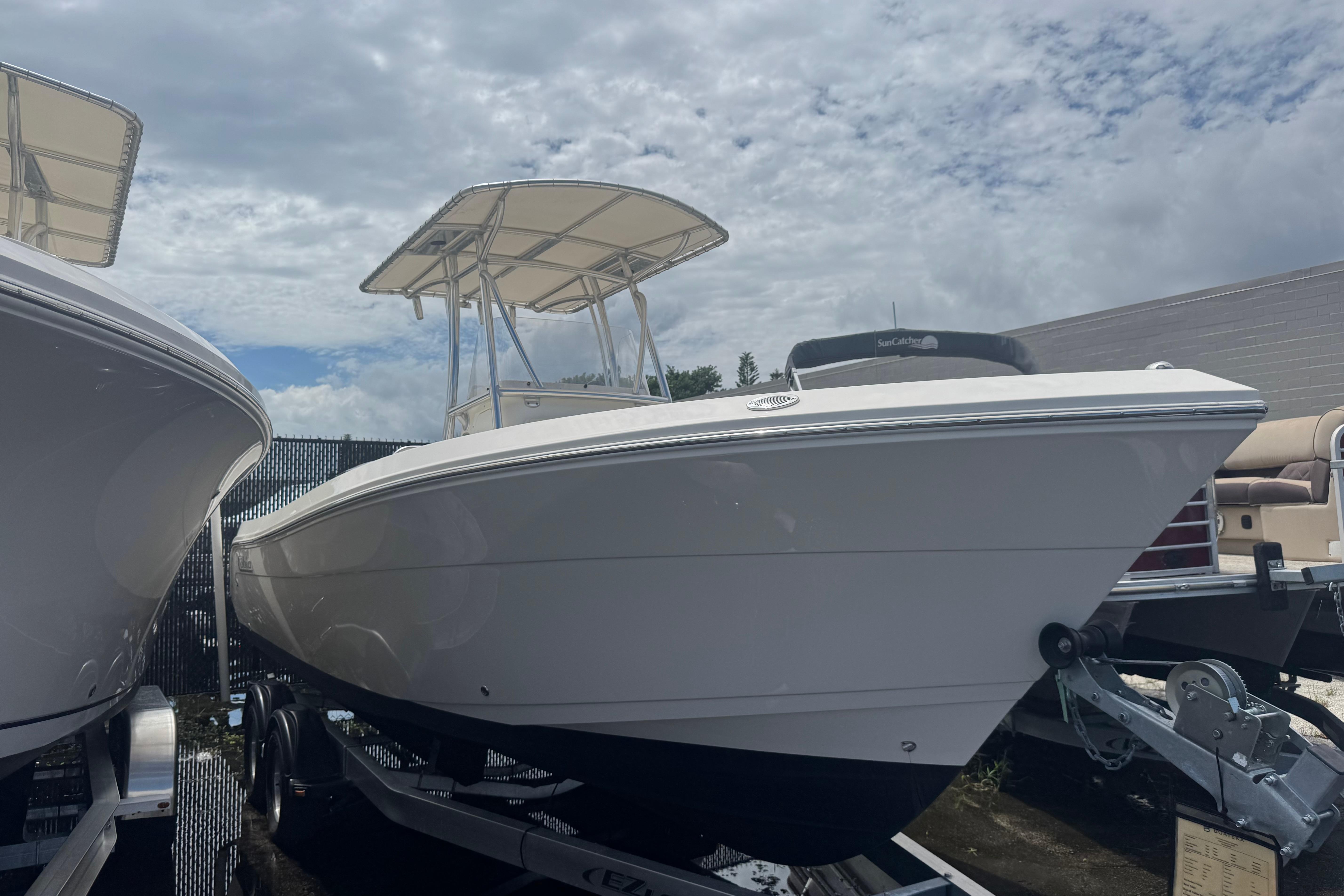 2022 Cobia 237 Center Console boat on trailer under cloudy sky.
