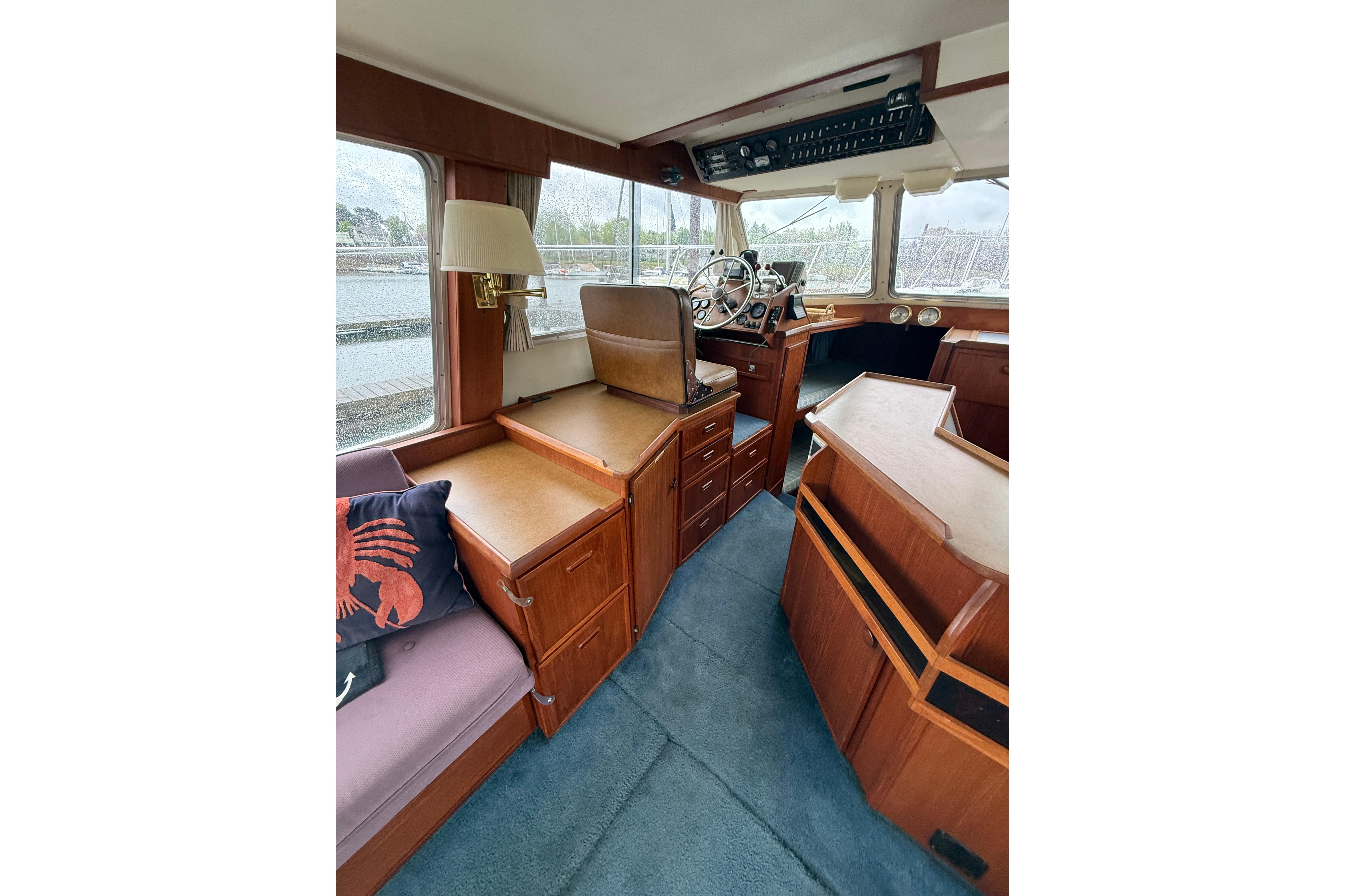 1979 Uniflite 37 Coastal Cruiser interior with wood cabinetry and steering wheel.
