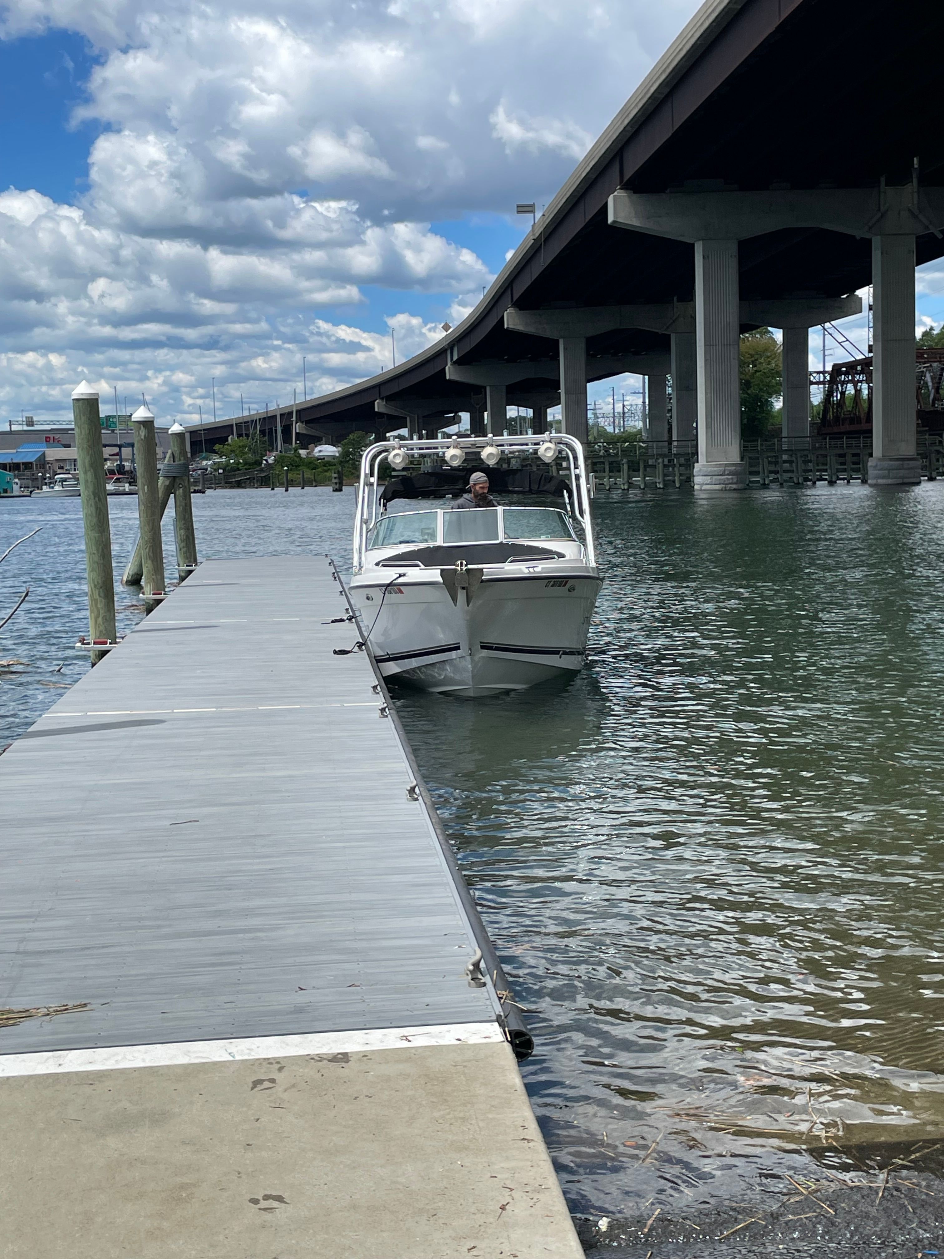 A white boat is docked, with a bridge in the background.