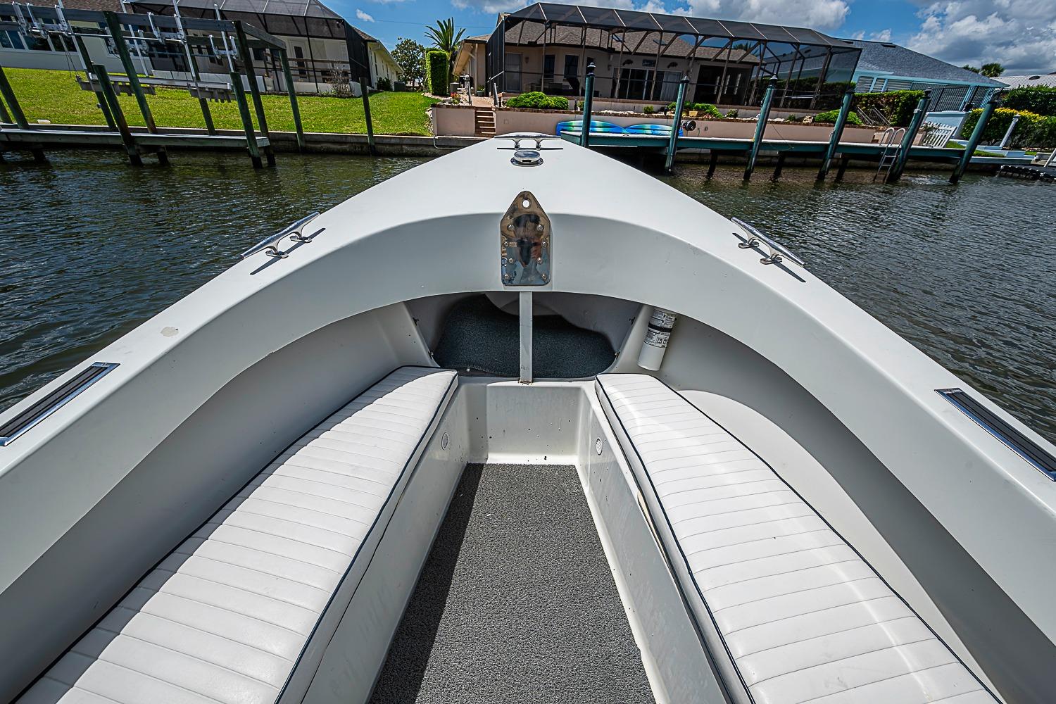 Front view of a 1969 custom boat with white seating and waterfront homes.