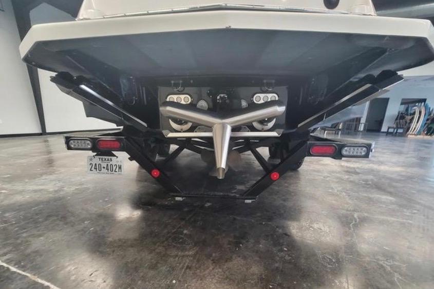 2022 MasterCraft NXT24 boat rear view in a showroom, showcasing propeller and trailer.