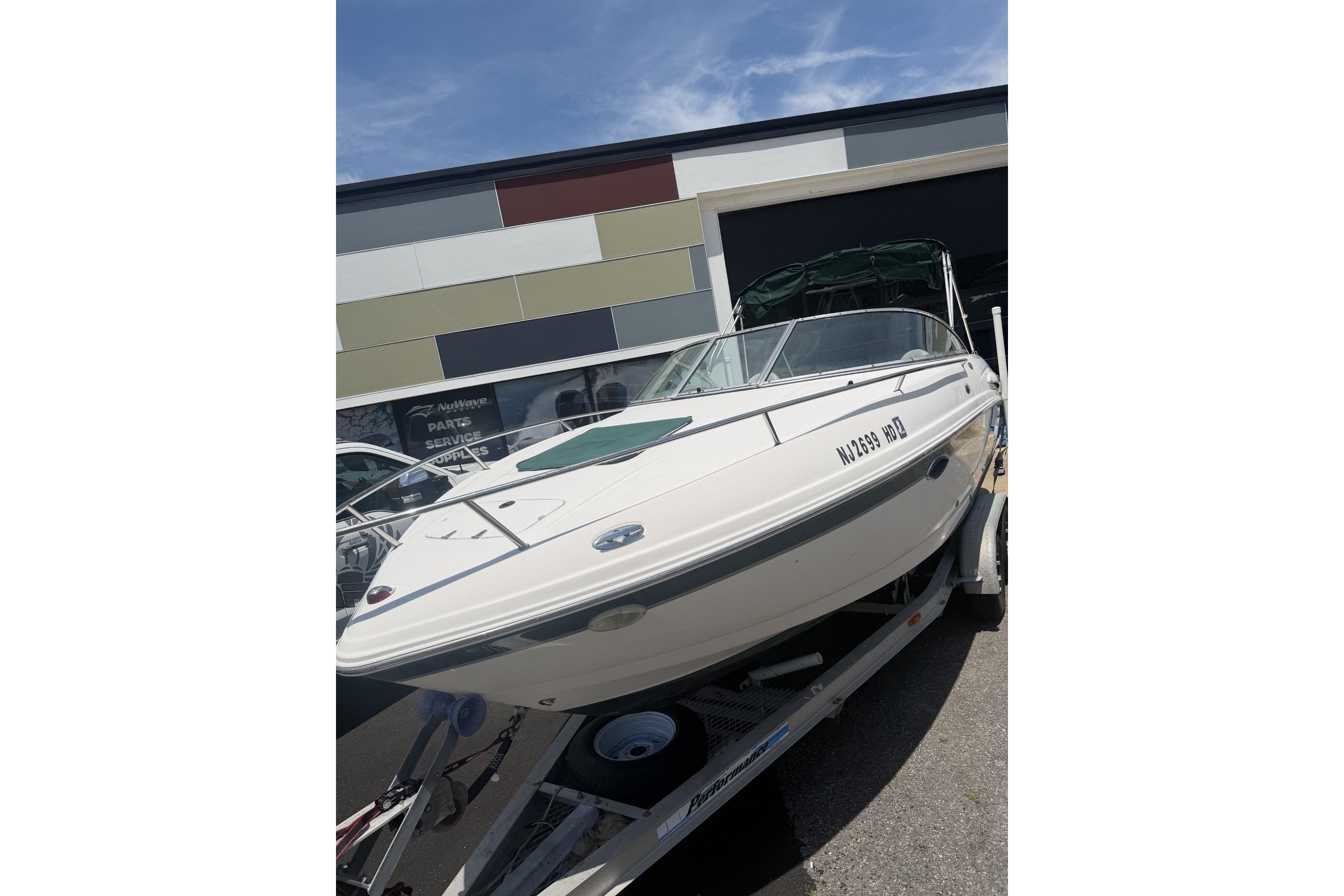 2001 Chaparral 235 SSi boat on trailer, parked outside a building under a clear sky.