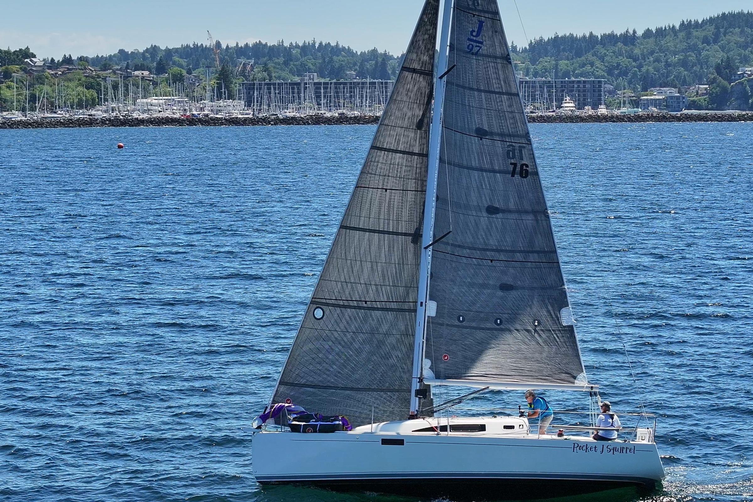 2018 J Boats J/97E sailing on a sunny day with scenic shoreline backdrop.