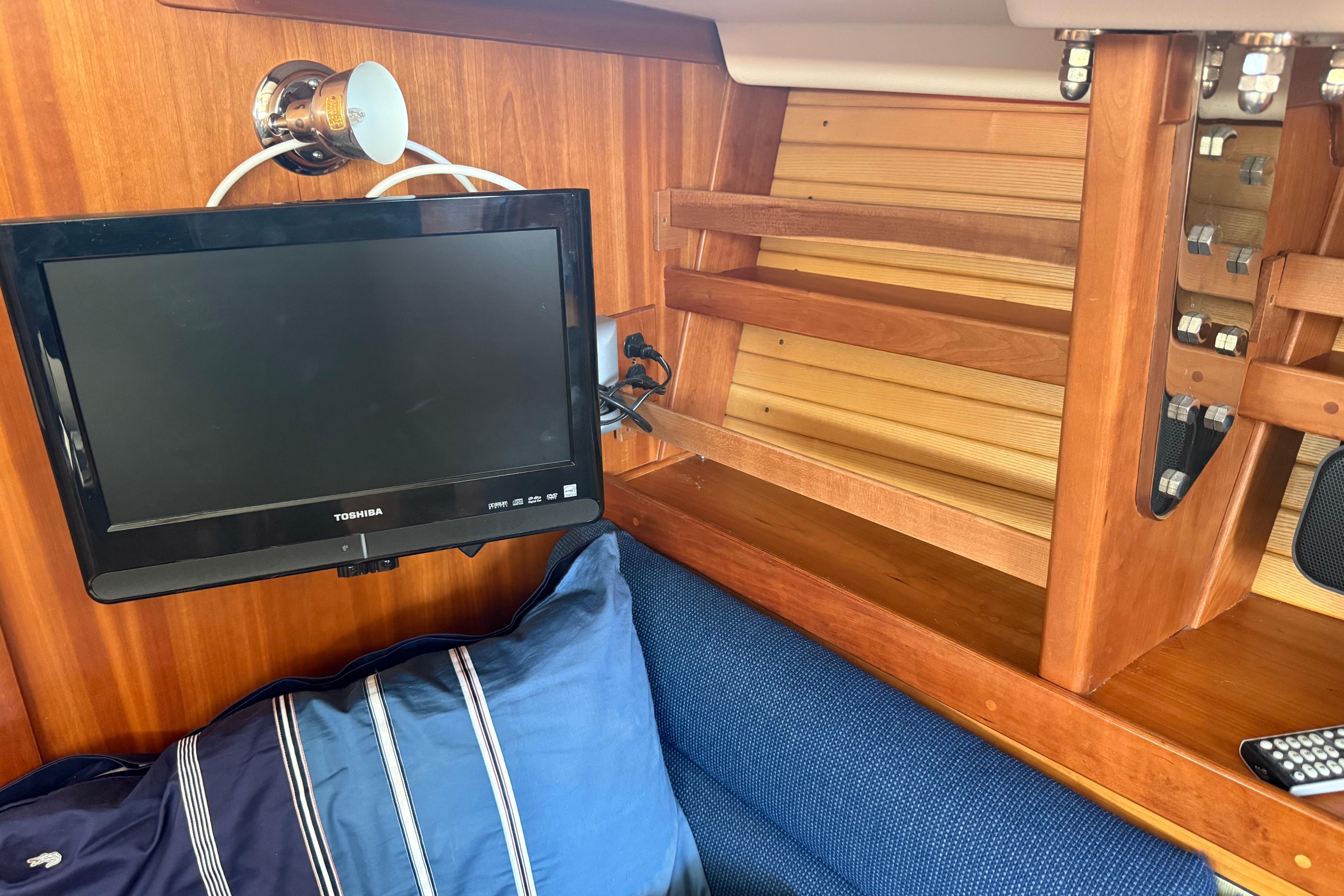 Interior of 2004 Sabre 386 yacht with TV, wooden shelves, and blue cushion.