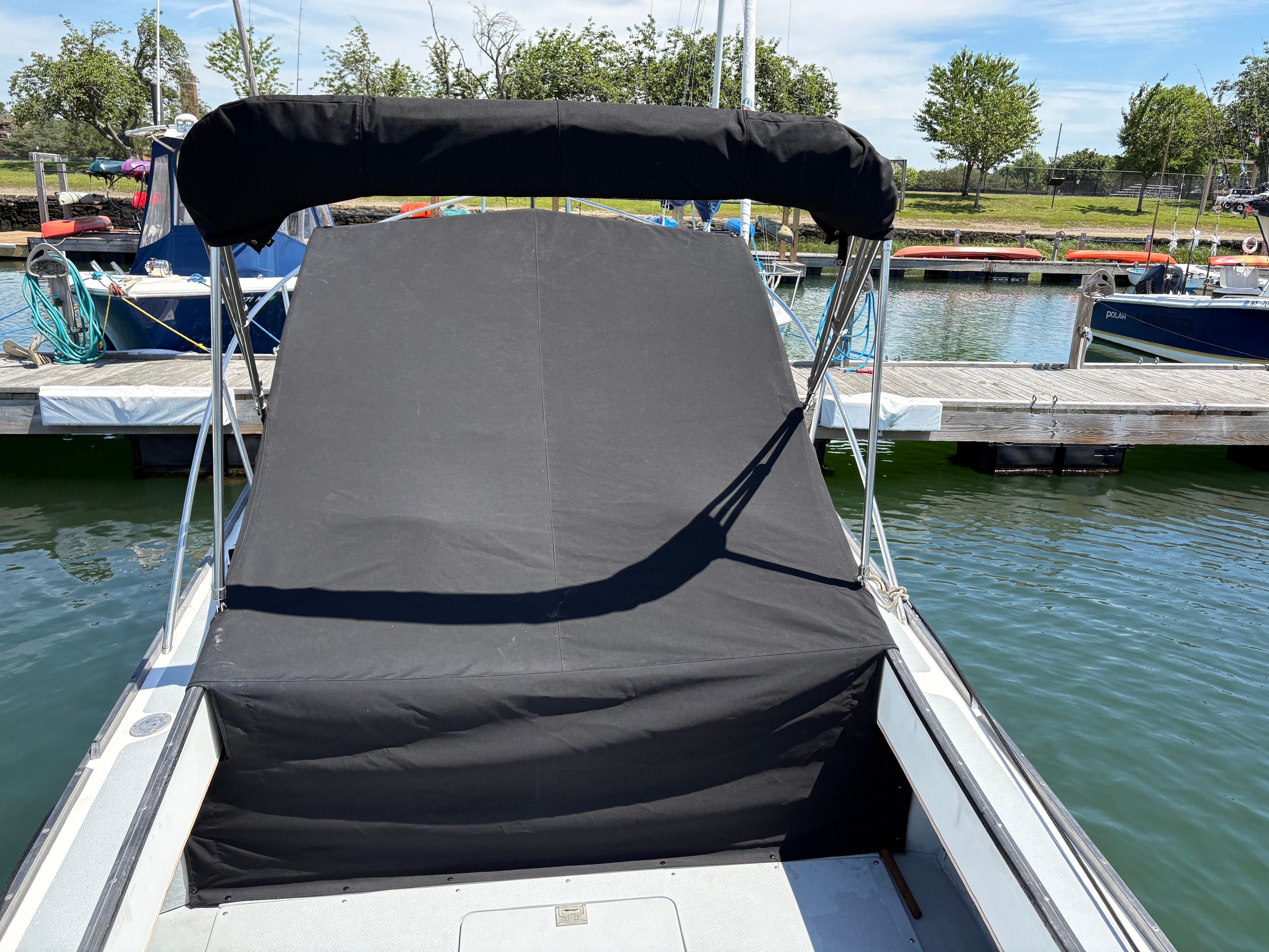 A 1990 Portsmouth 22 boat with a black cover docked at a marina.