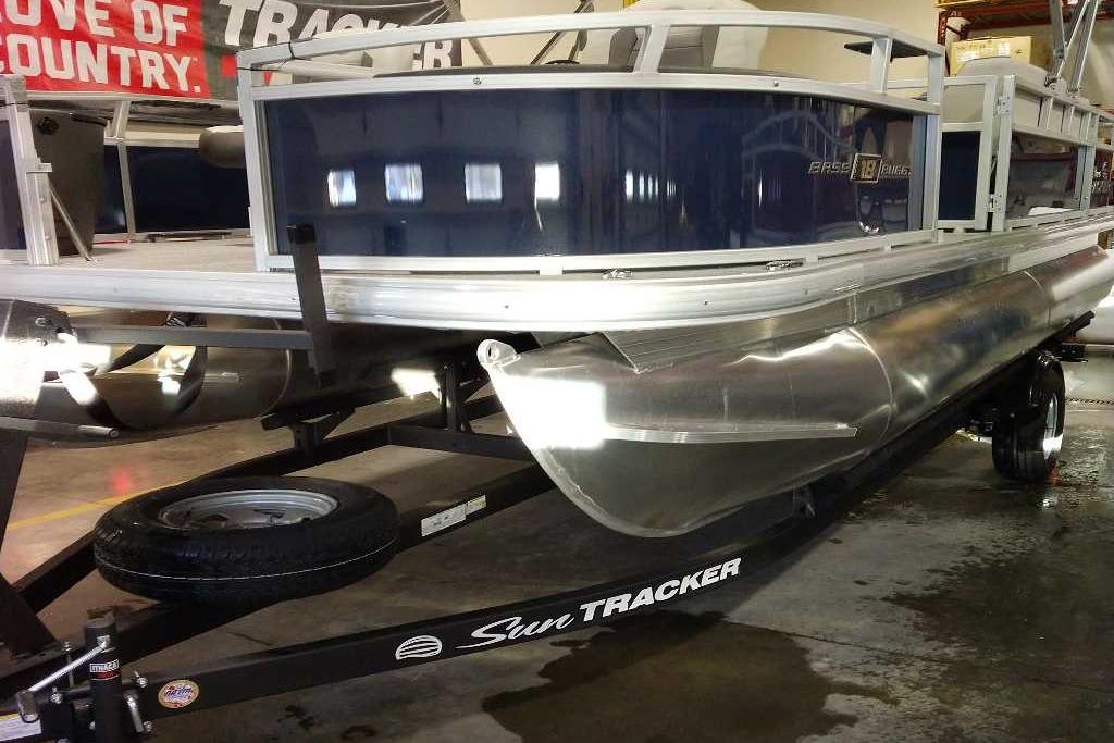 2026 Sun Tracker Bass Buggy 18 DLX pontoon boat on trailer in showroom.