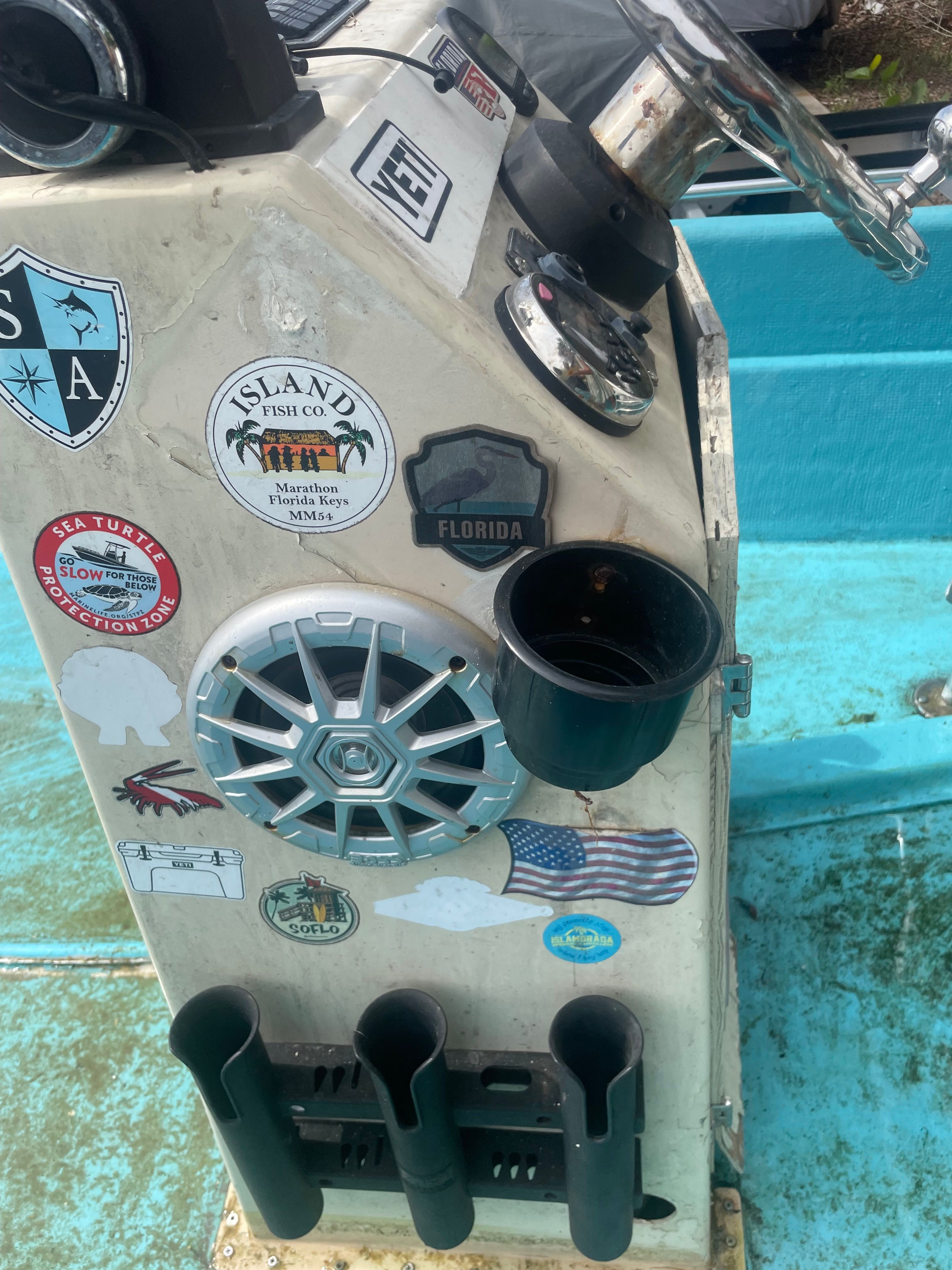 A boat with a control panel covered in stickers and a blue deck.