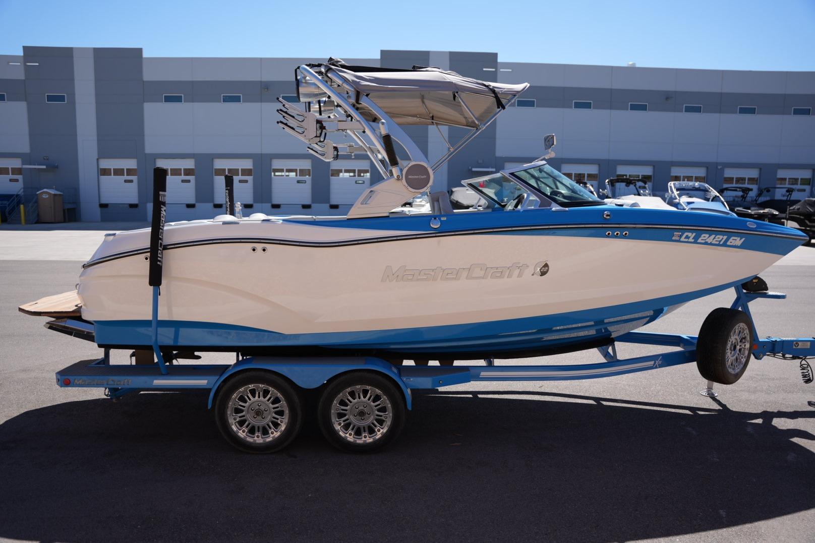 2020 MasterCraft X22 boat on trailer, blue and white design, parked outdoors.