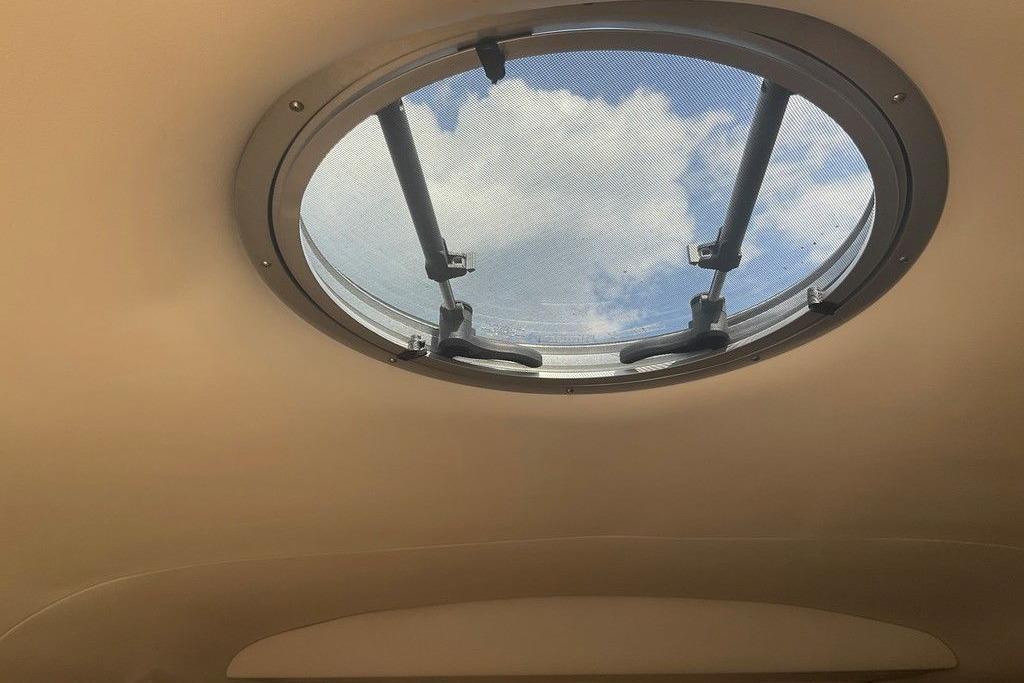 Circular hatch view from 2015 Crownline 236 SC boat, showing blue sky and clouds.