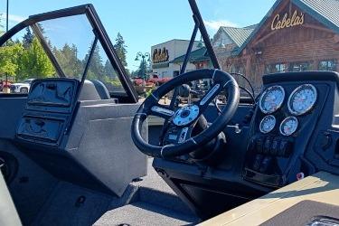 2026 Tracker Targa V-19 Combo boat dashboard with steering wheel and gauges, outside Cabela's store.