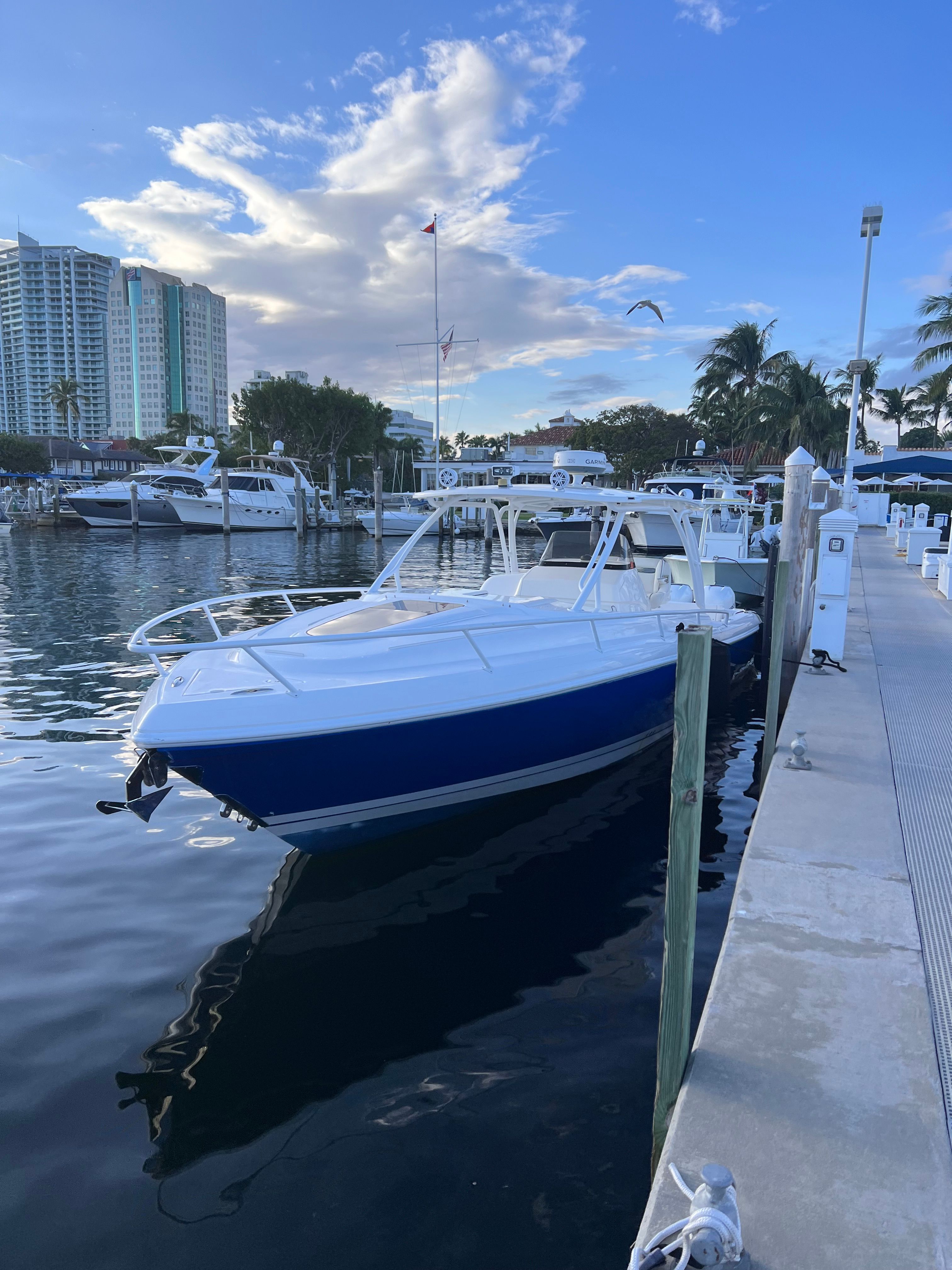 A 2014 Intrepid 375 Walkaround docked at a marina, with buildings and palm trees nearby.