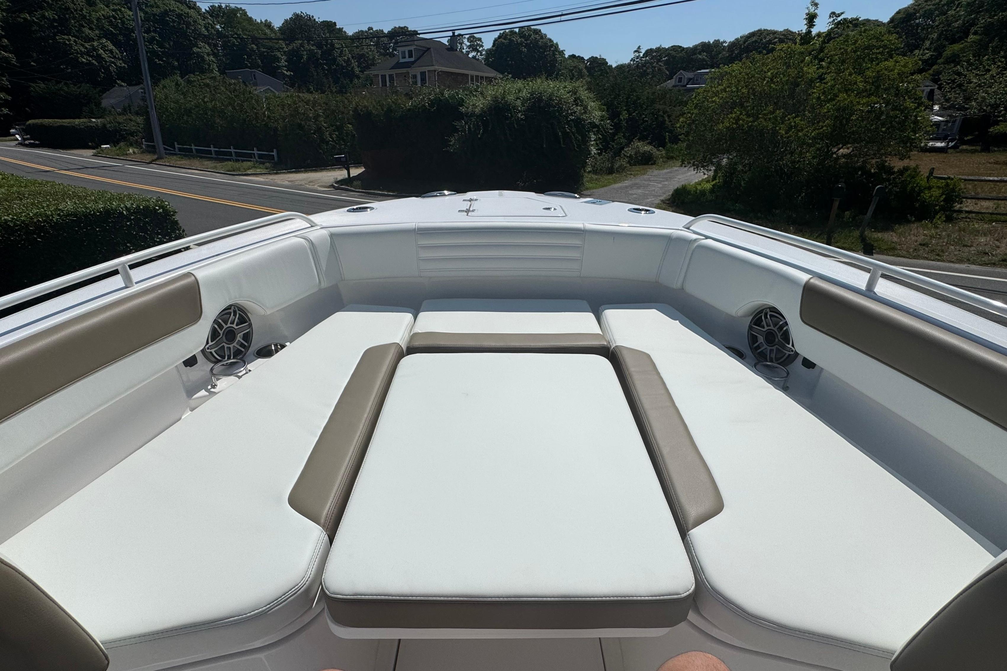2026 Edgewater 250CC boat interior with cushioned seating and speakers, parked near a road.