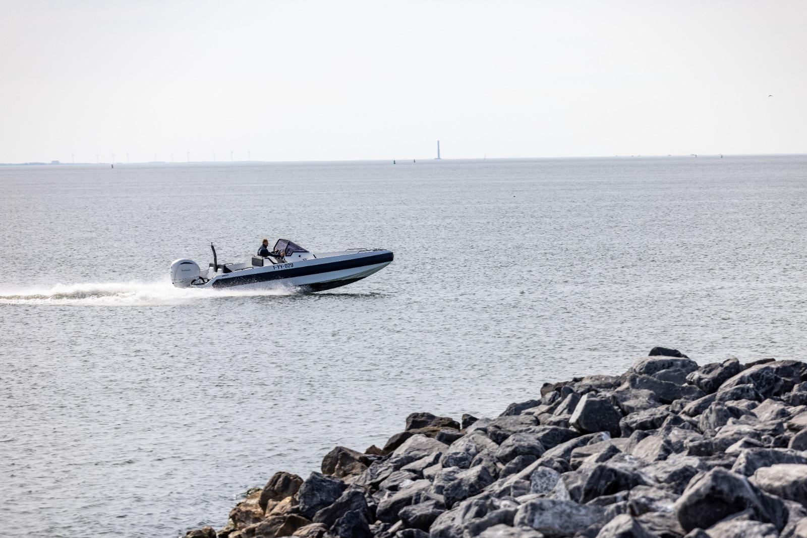 Speedboat Iron 707 cruising near rocky shoreline, 2022 model.