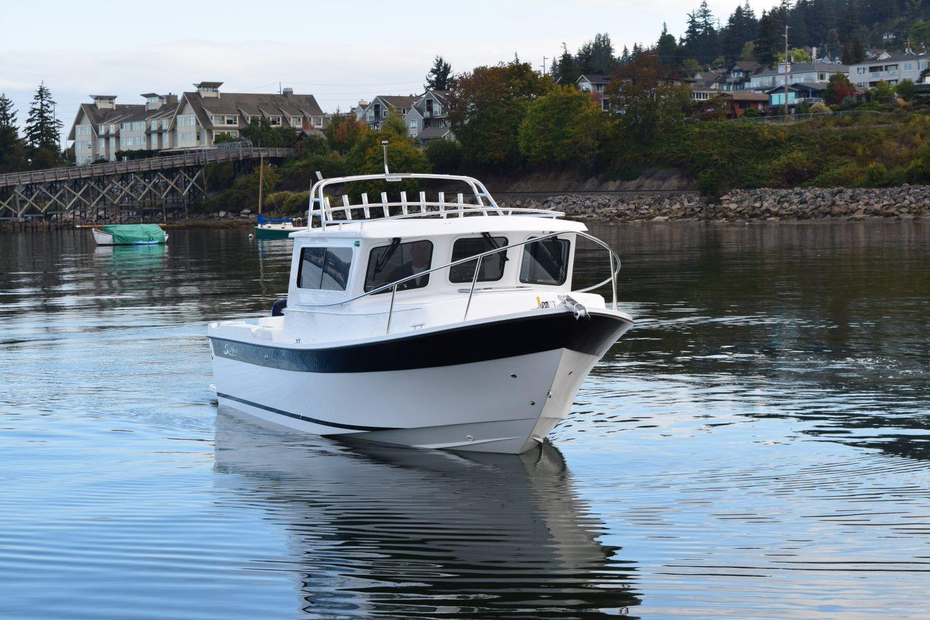 2026 Sea Sport Kenai 2600 boat on calm water near a scenic shoreline.