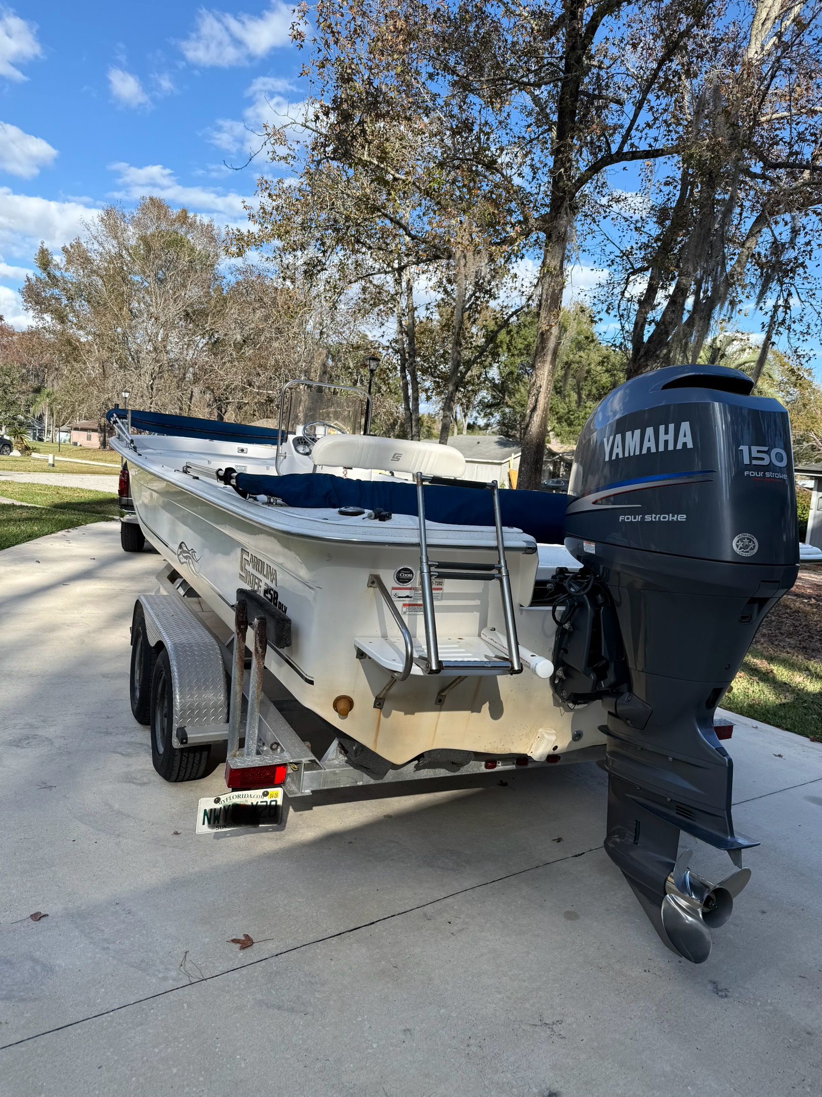 A 2011 Carolina Skiff 258 DLV on a trailer, surrounded by trees.